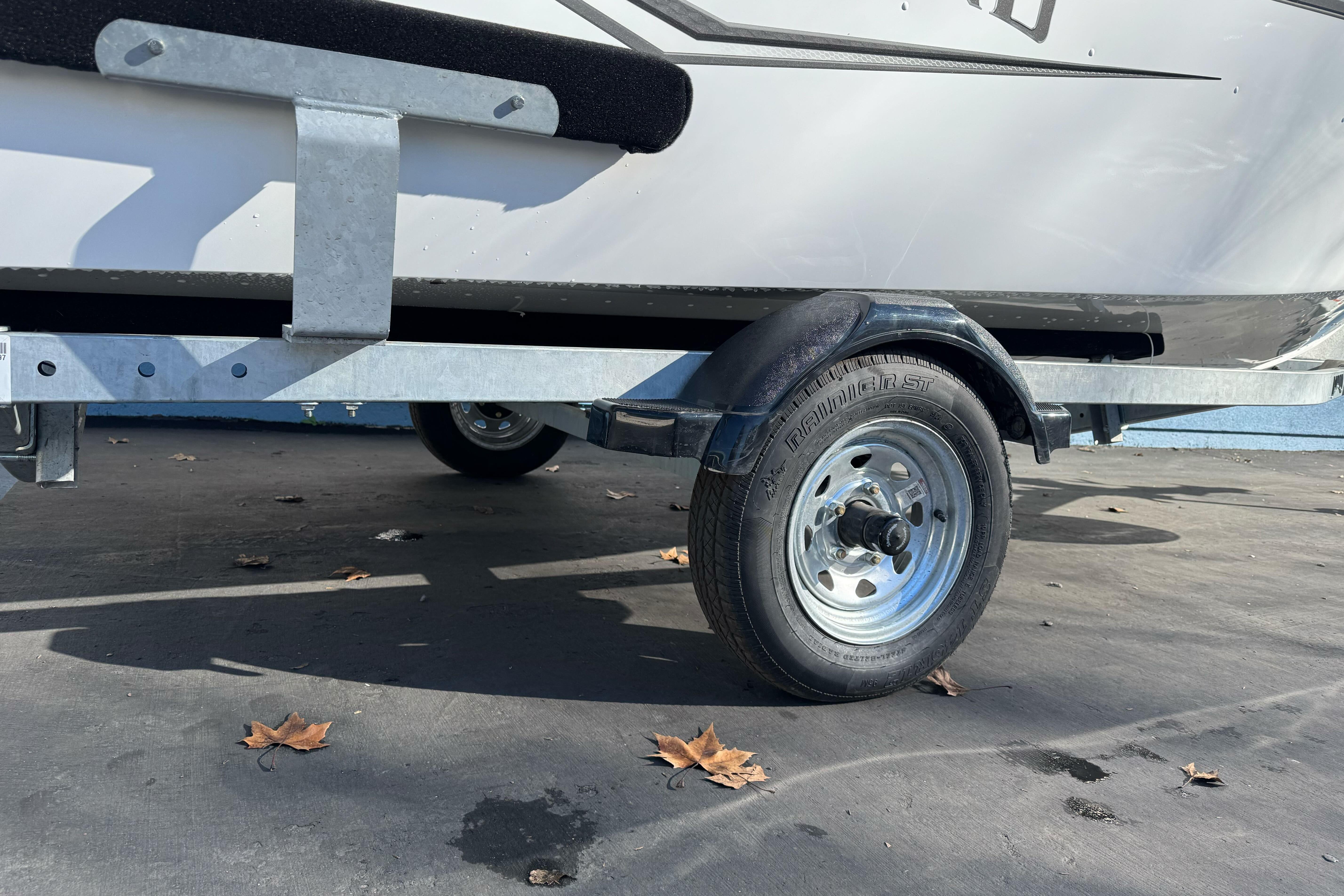 2026 Lund 1650 Angler SS trailer wheel on pavement with fallen leaves.