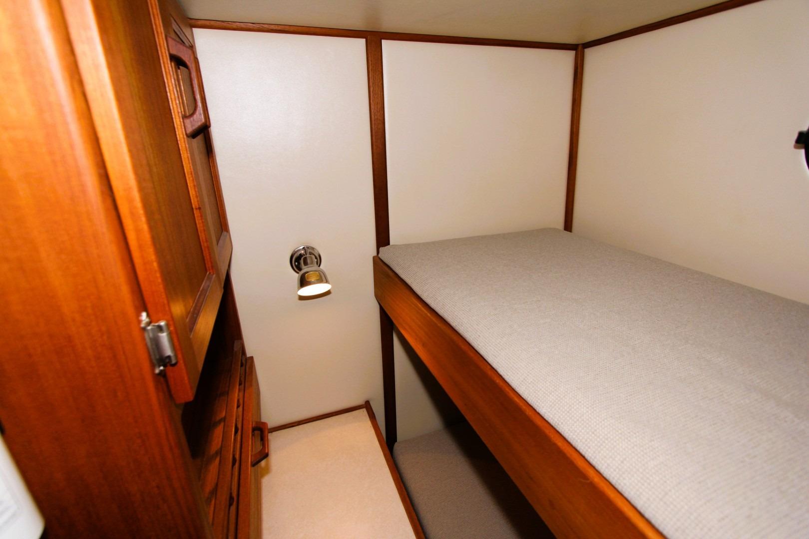 Cozy cabin interior of 2002 Nordic Tug 37 with wooden furnishings and a single bed.