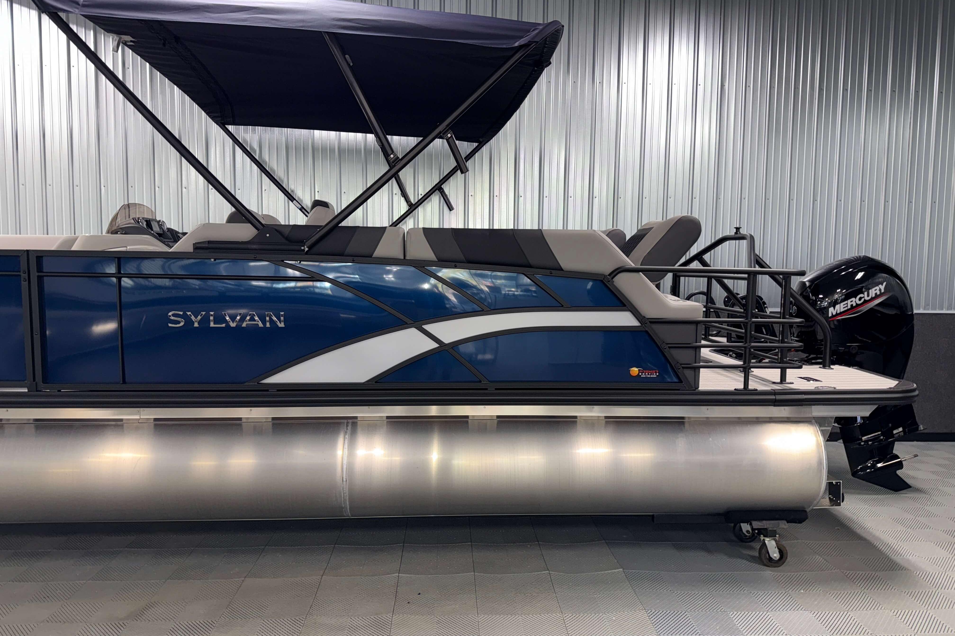 2026 Sylvan L3 SLZ pontoon boat with Mercury outboard motor in showroom.