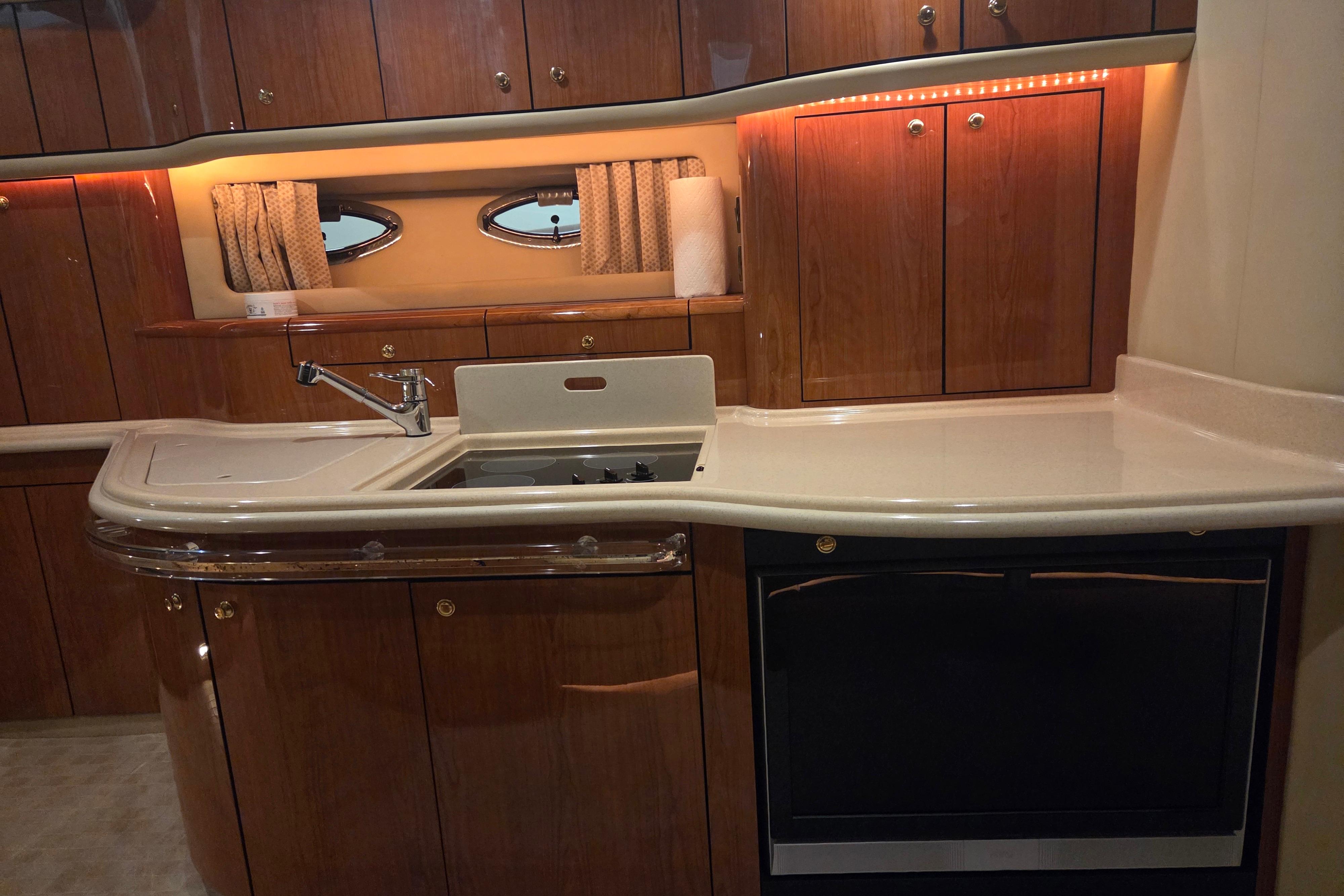 Luxurious kitchen interior of 2000 Sea Ray Sundancer 540 yacht with wood cabinetry.