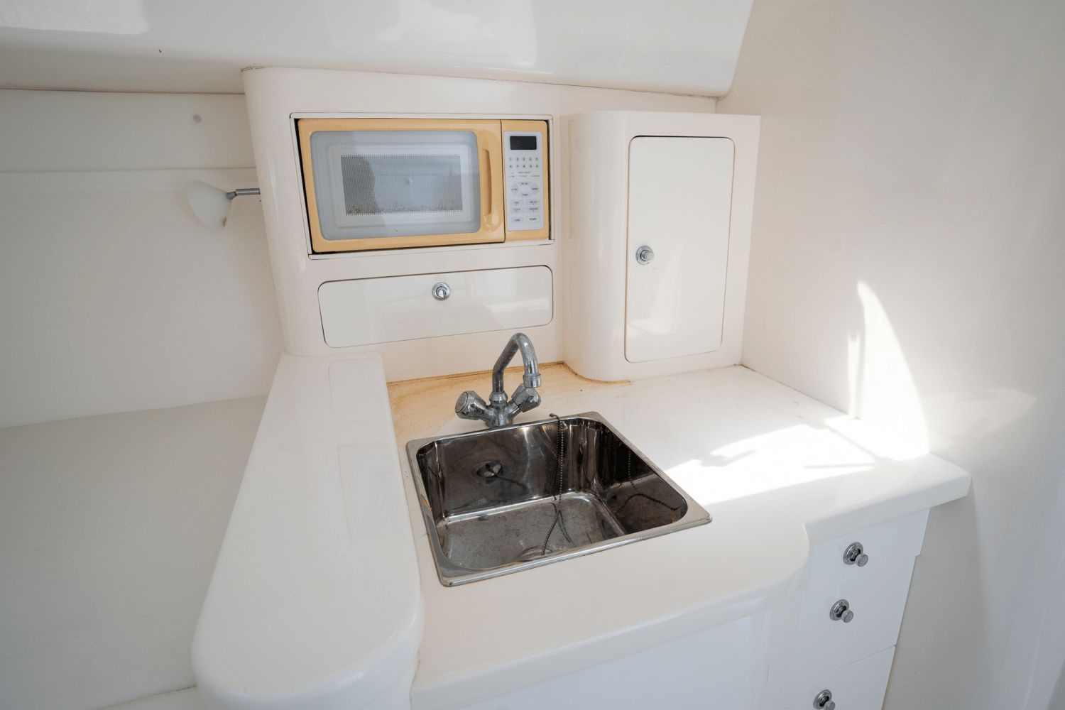 Compact kitchenette in a 2005 Intrepid 348 WA boat with sink and microwave.