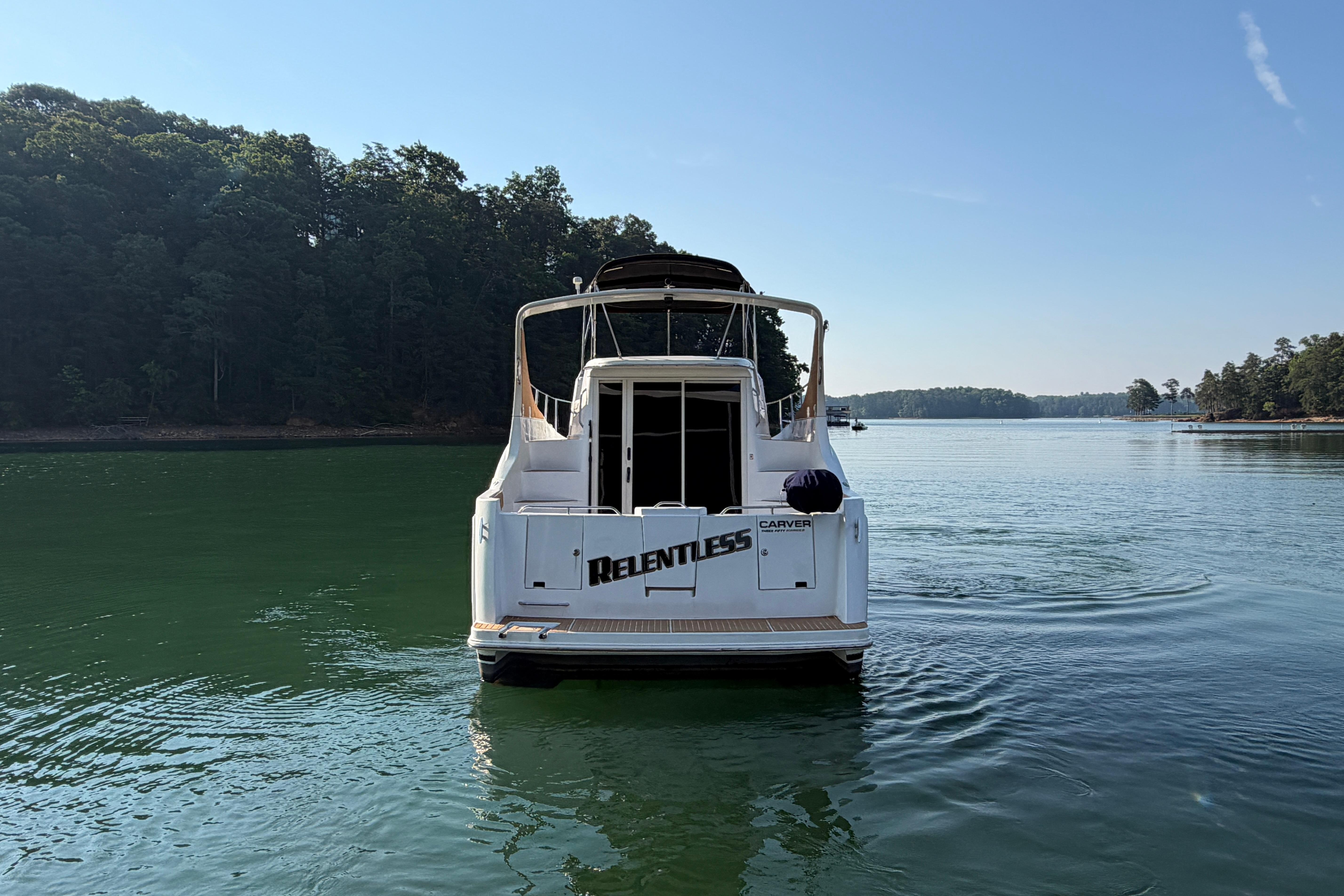 2003 Carver 350 Mariner yacht on serene lake with forested shoreline.