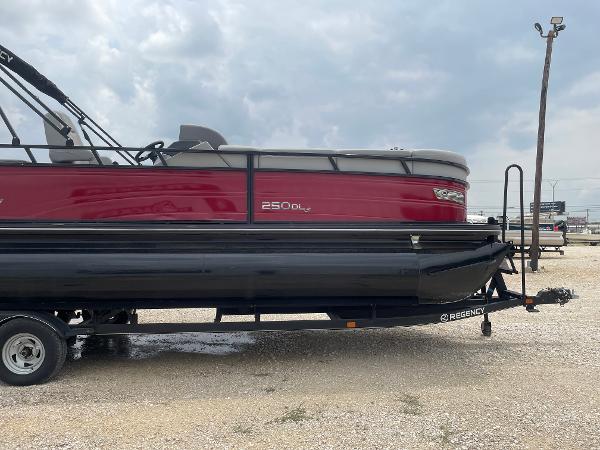 2023 Regency 250DL3 pontoon boat on trailer, red and black design, parked outdoors.