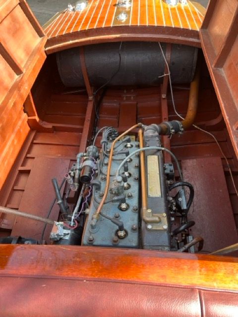 The engine compartment of a 1938 Chris-Craft Custom Deluxe Runabout shows a well-preserved engine.