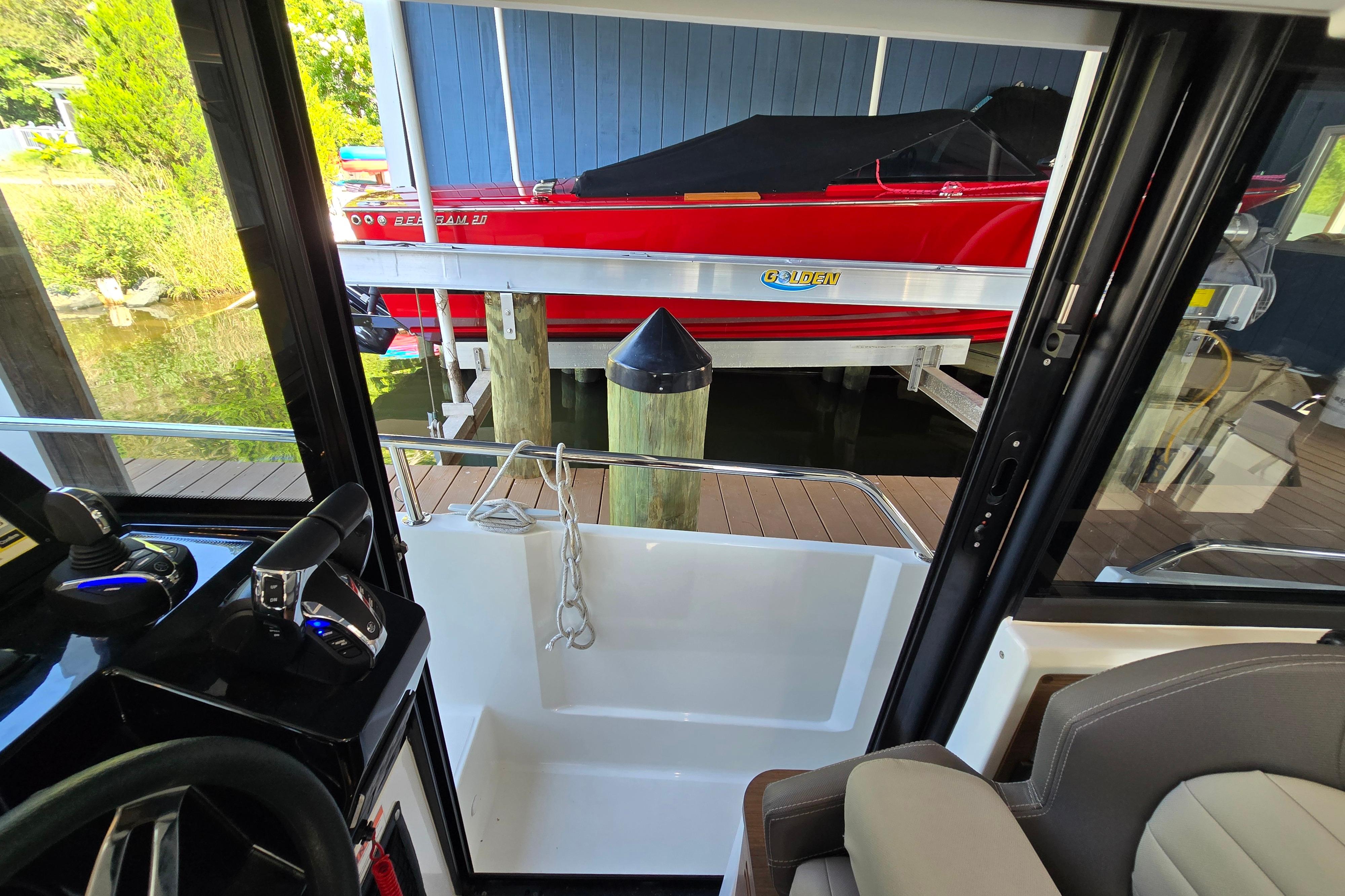 View from inside a boat docked at a pier, with a red boat in the background.