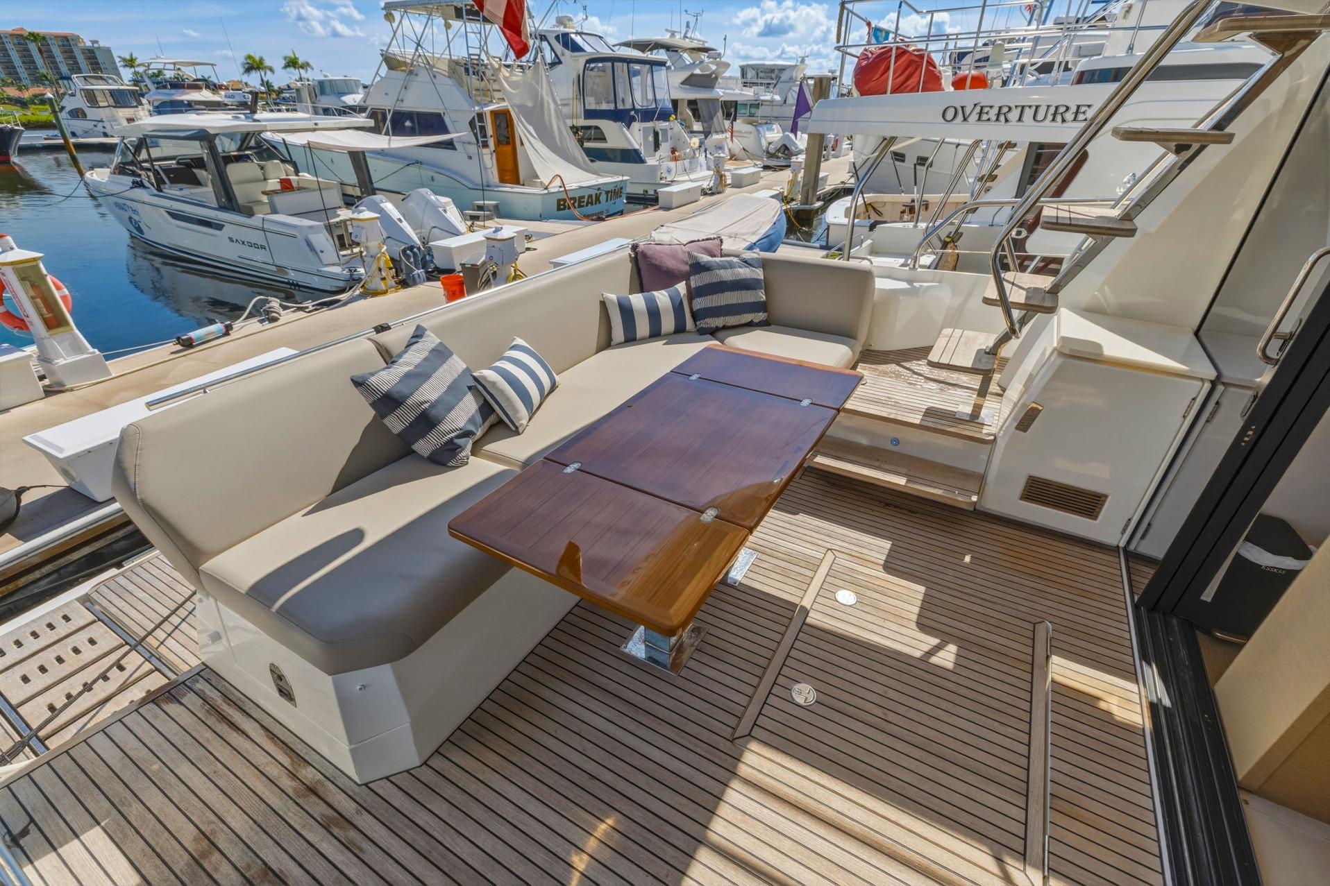 Luxurious 2022 Prestige 520 yacht deck with seating and table, docked at marina.