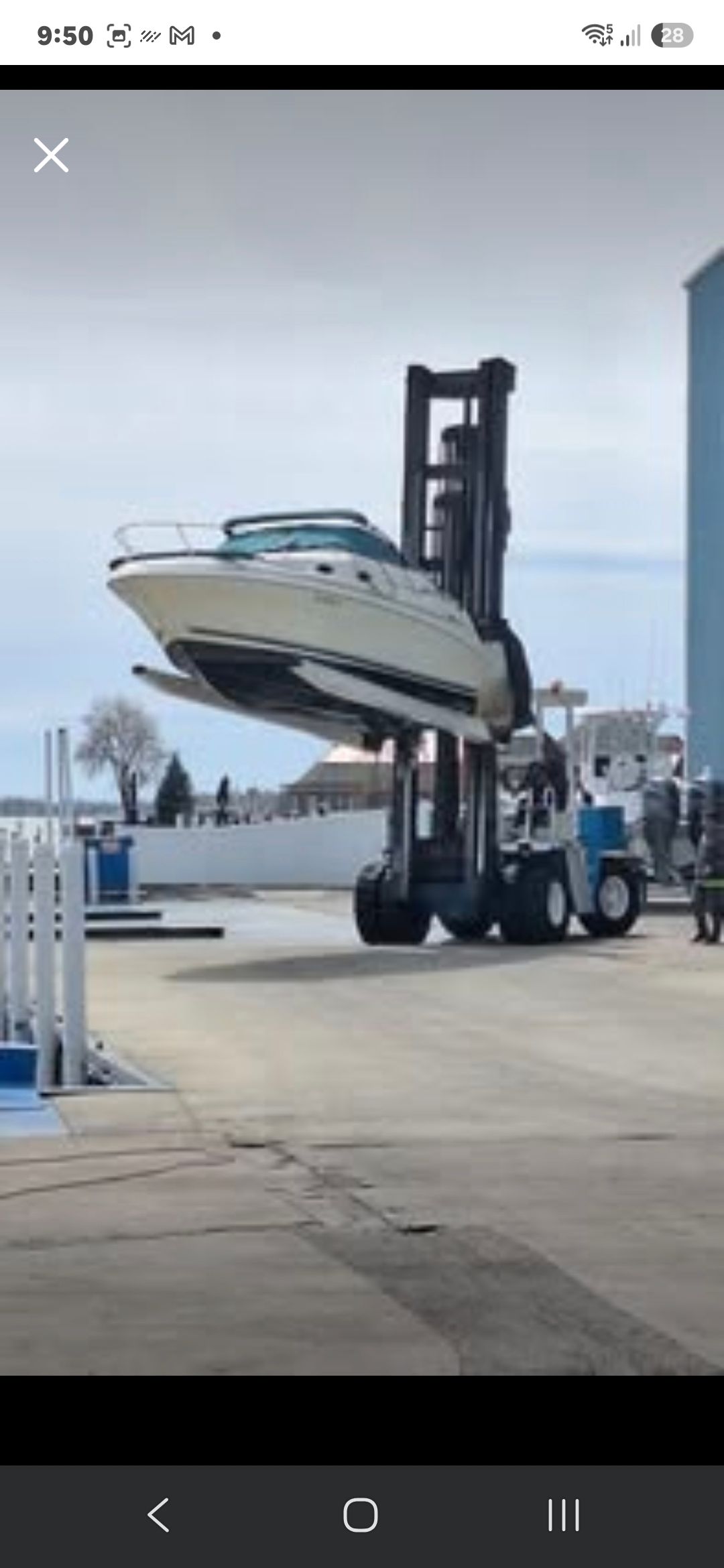 A 1998 Sea Ray 240 Sundancer being lifted on land by a forklift.
