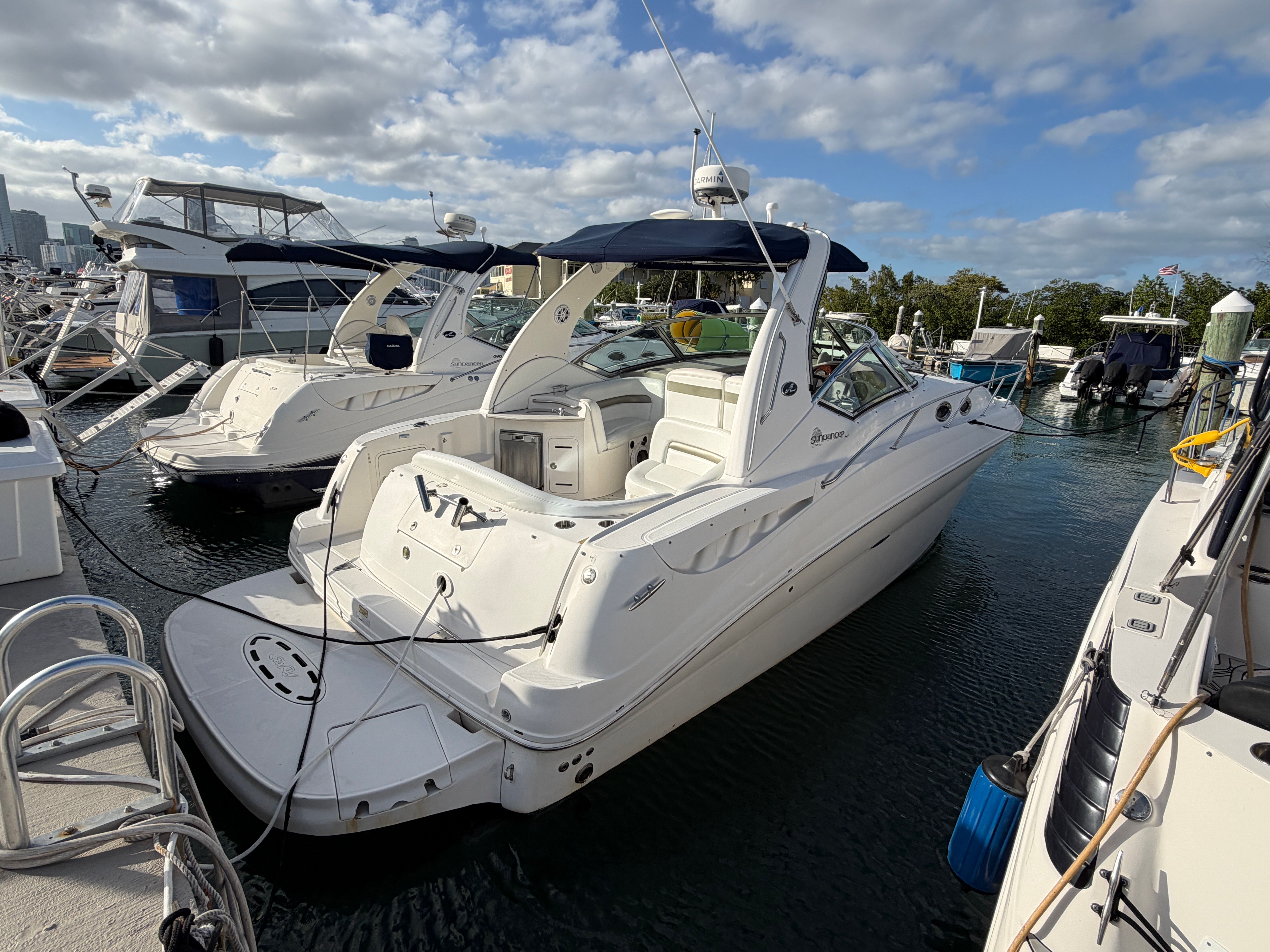 A 2006 Sea Ray Sundancer 320 docked in sunny weather. It features a sleek, white design.