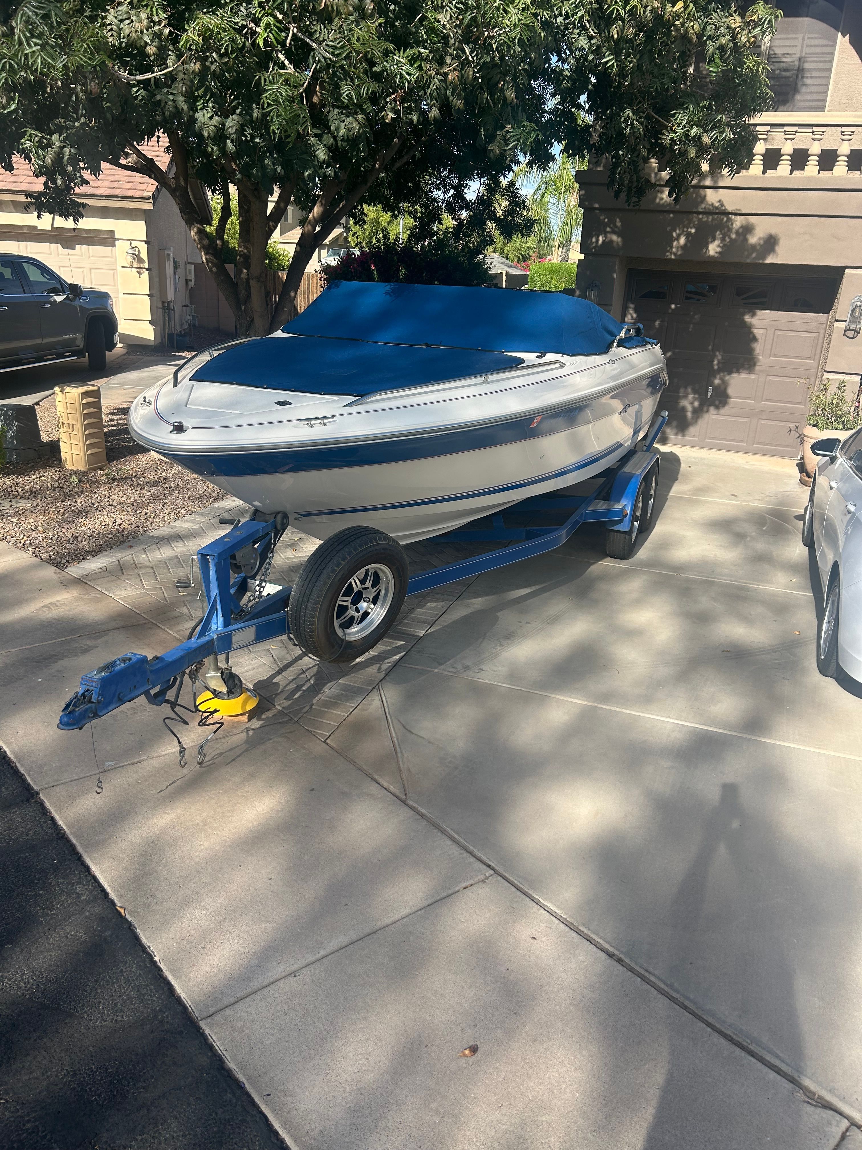 A 1994 Sea Ray 185 Sport boat on a blue trailer in a driveway.