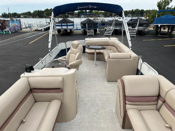 A 2018 South Bay S224CR pontoon boat with beige seating and a blue sunshade.