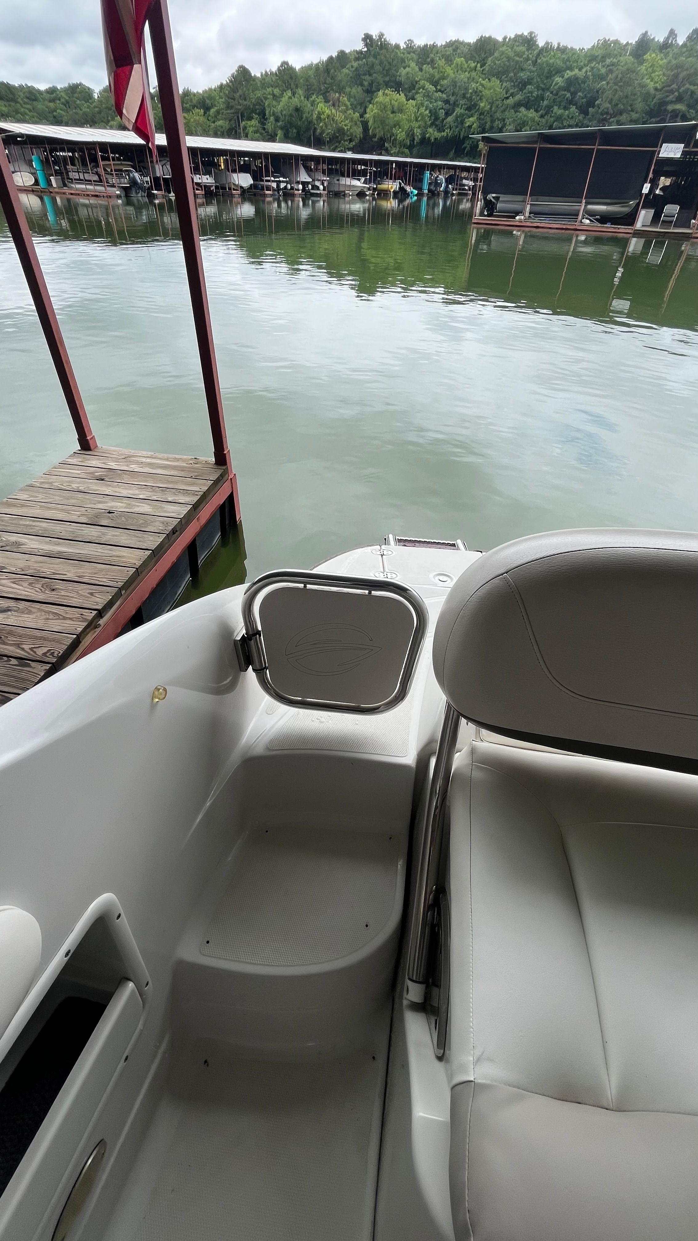 A boat with white seating and a small gate at the stern, docked by a pier.