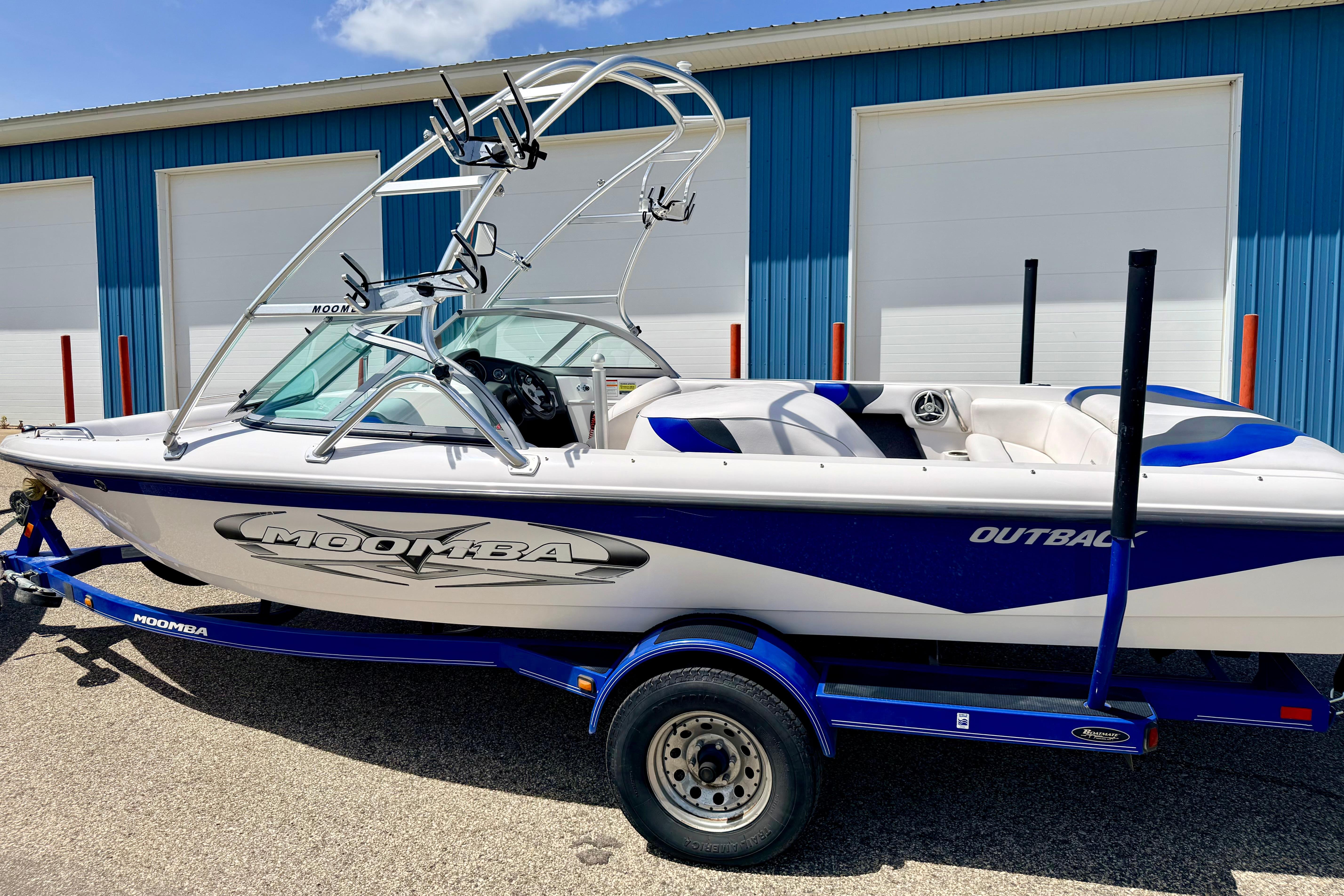 2008 Moomba Outback V boat on trailer, parked near blue building.