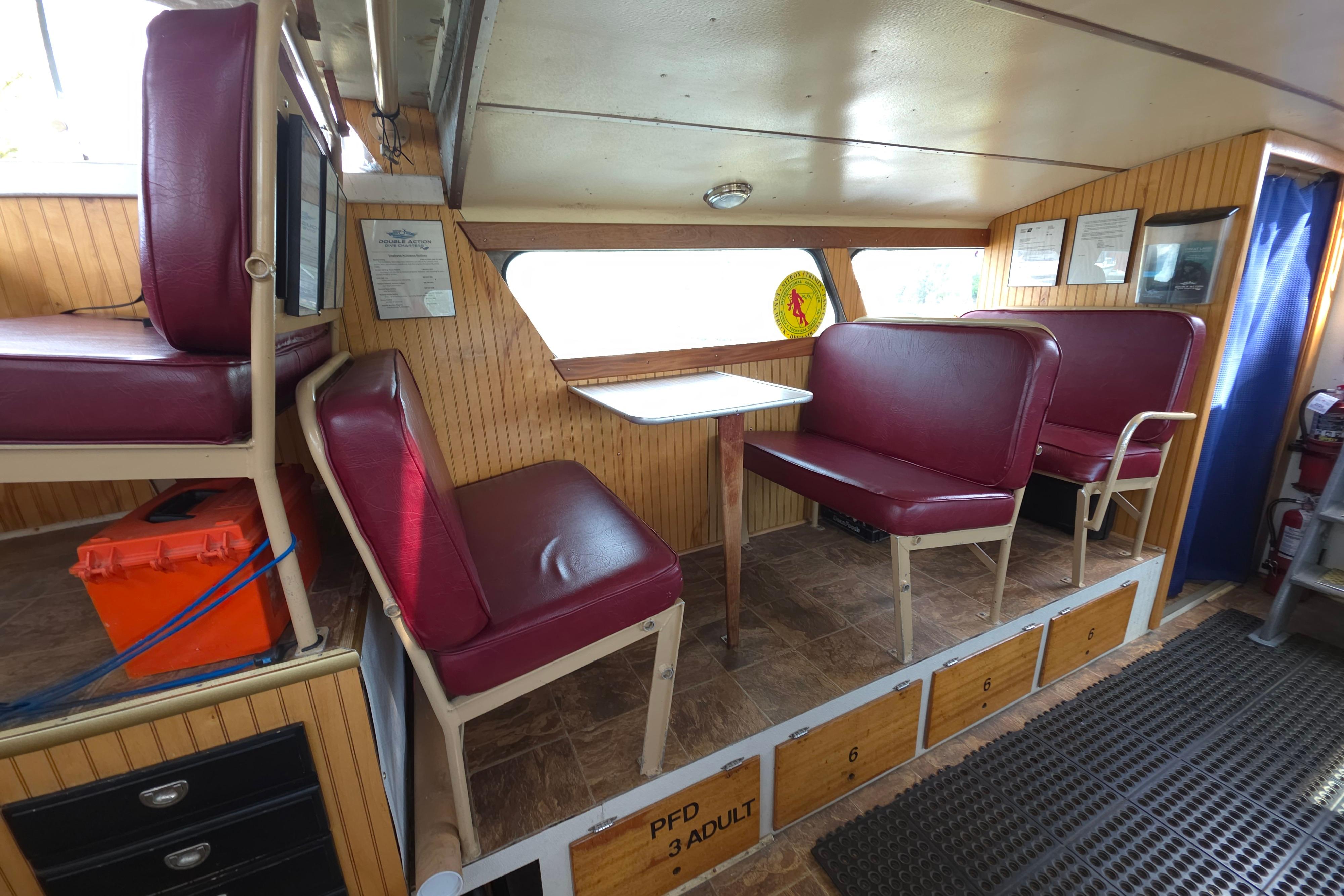 Interior of a 1974 Breaux's Bay Craft passenger boat with red seating and wood paneling.