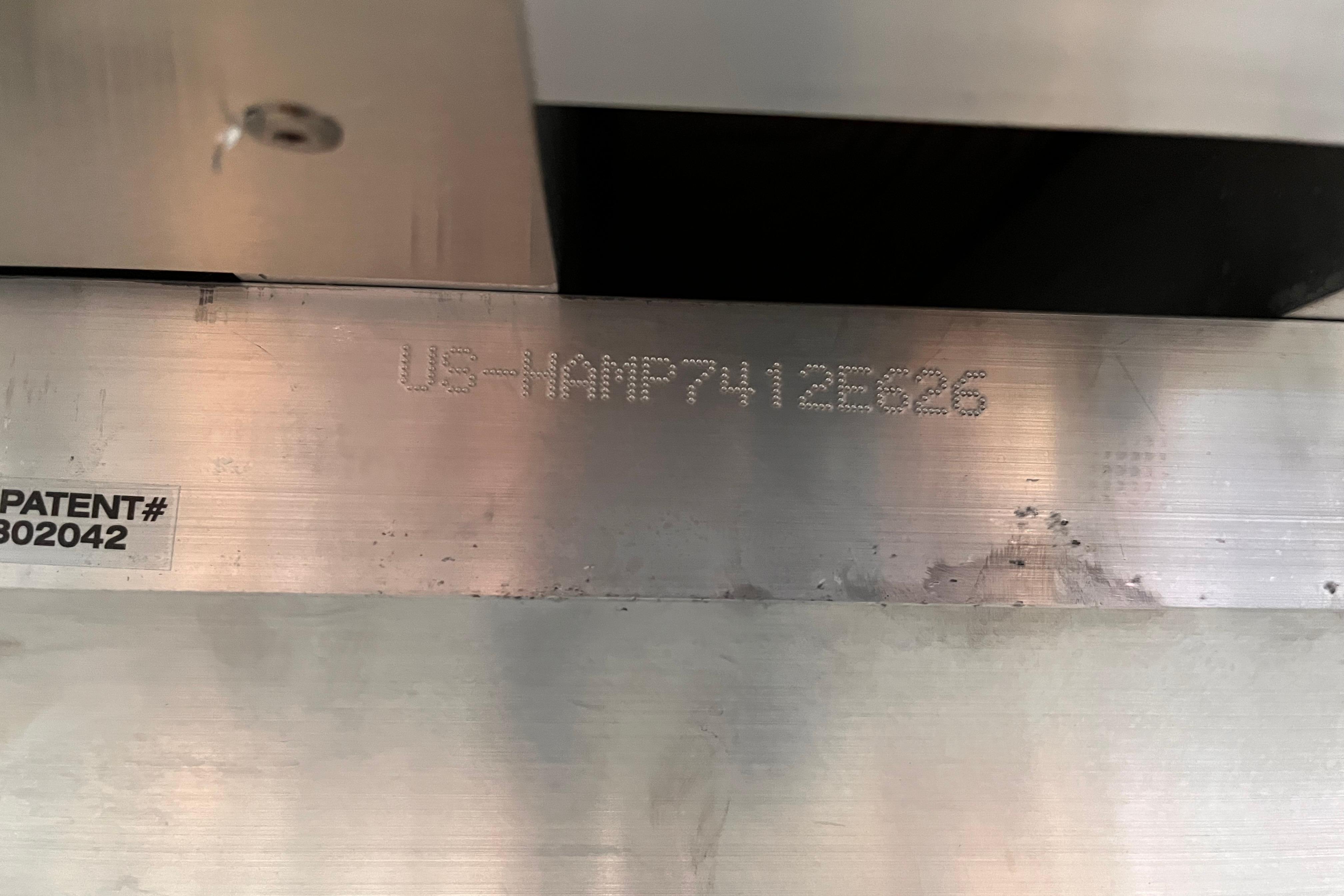 Close-up of Harris Sunliner 250 (2026) metal part with patent number and serial code.