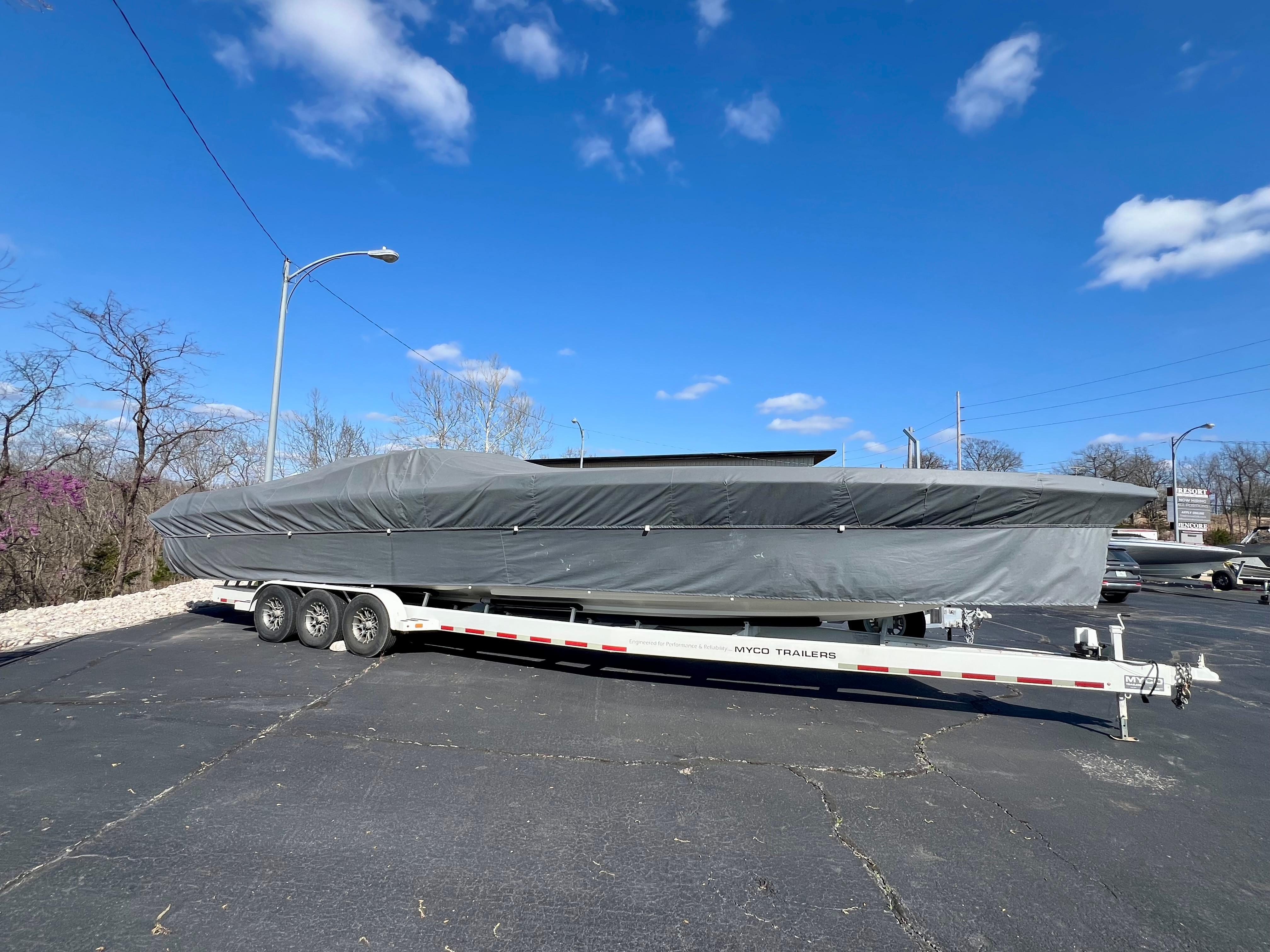 Covered 1999 Black Thunder 430 Flat Deck boat on trailer under blue sky.