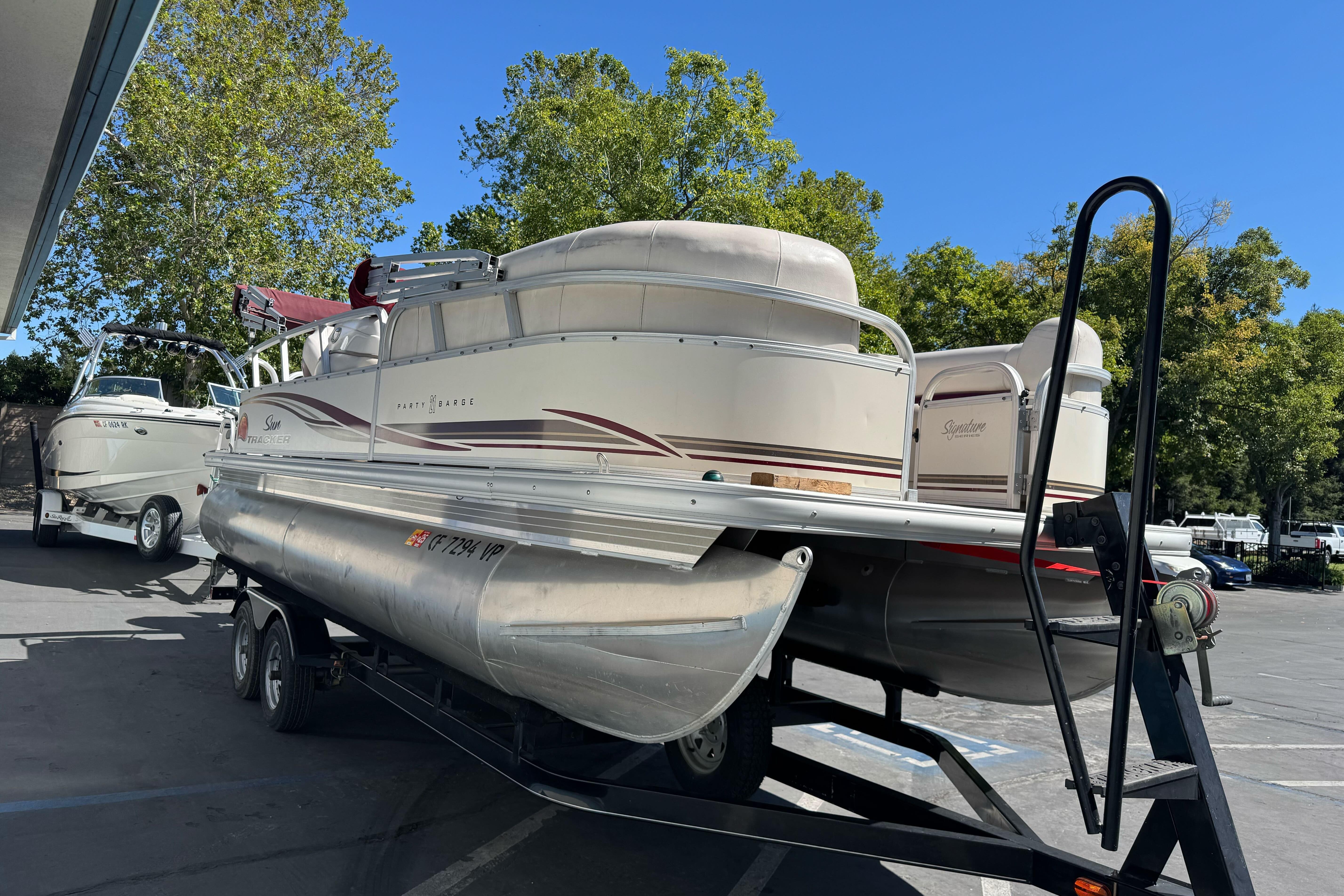 2011 Sun Tracker Party Barge 21 pontoon boat on trailer, parked outdoors.