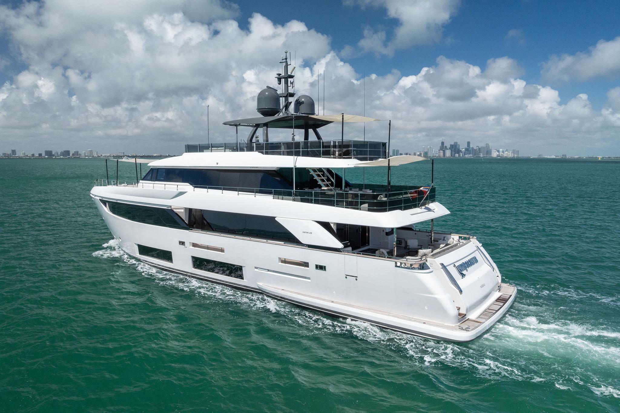 Luxurious 2023 Custom Line Navetta 33 yacht cruising on open sea with city skyline backdrop.