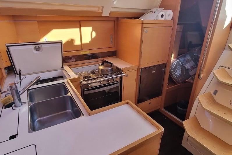 Compact kitchen in a 2008 Elan 410 yacht with stove, sink, and storage.