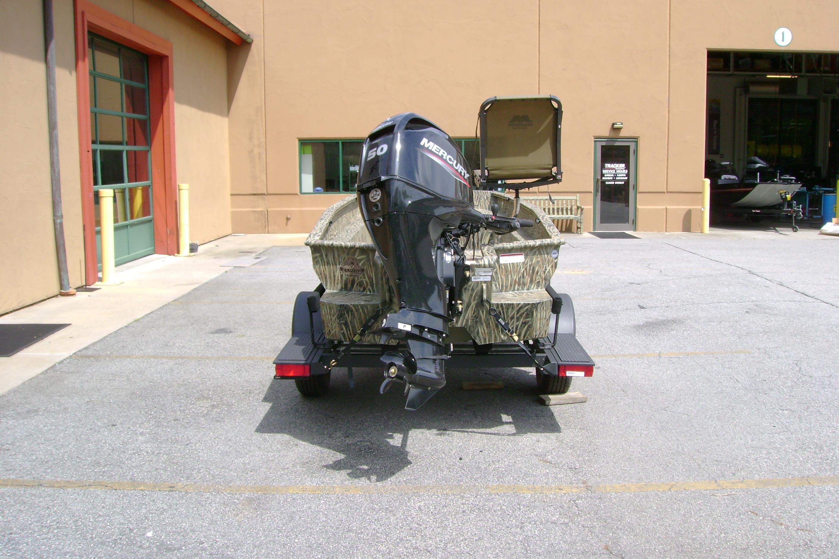 2026 Tracker Grizzly 1650 T Prairie Wings Edition boat with Mercury engine, parked outside a building.