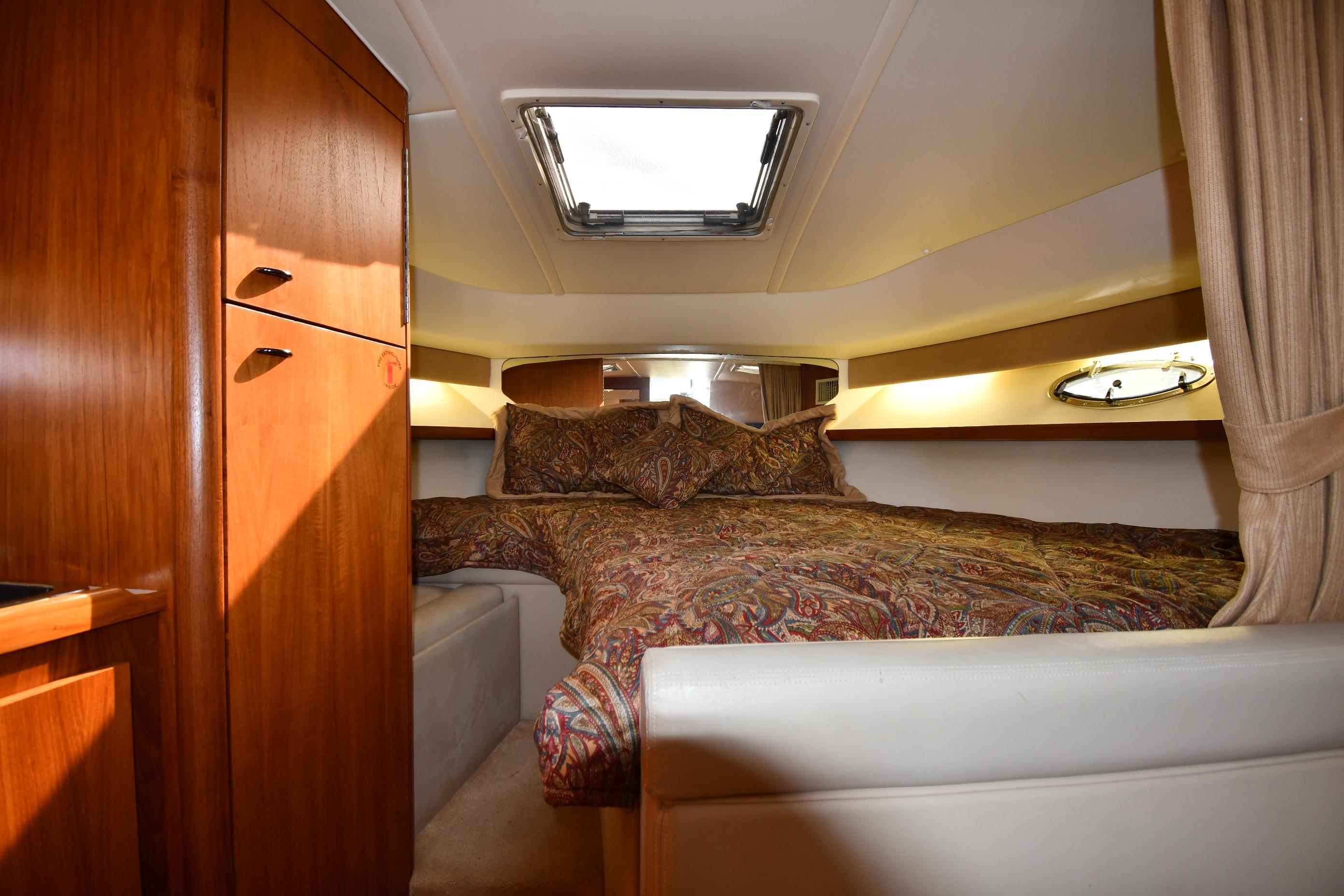 Cozy cabin interior of 1998 Tiara Yachts 3100 Open with wood cabinetry and patterned bedding.