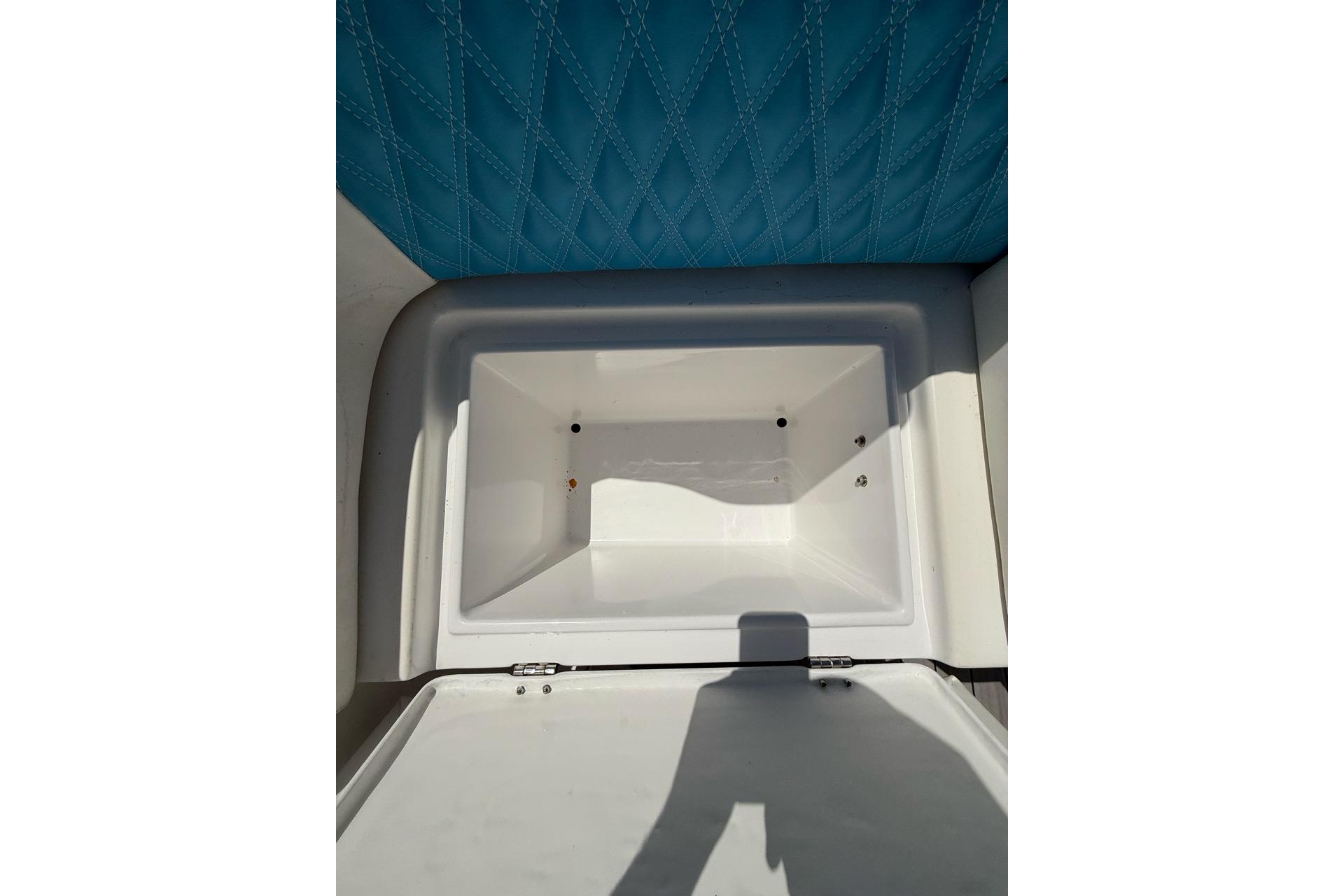 Open storage compartment on 2021 Custom Infusion 34 CC boat with blue quilted upholstery.