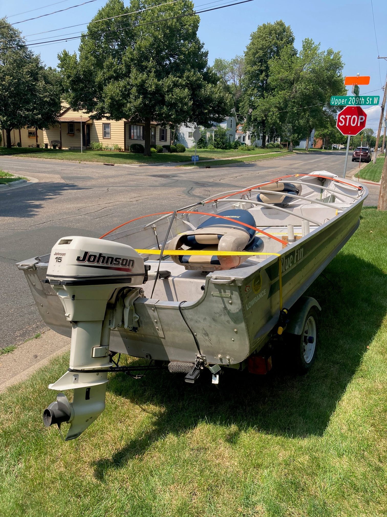 A boat on a trailer in a residential area, featuring a Johnson outboard motor.