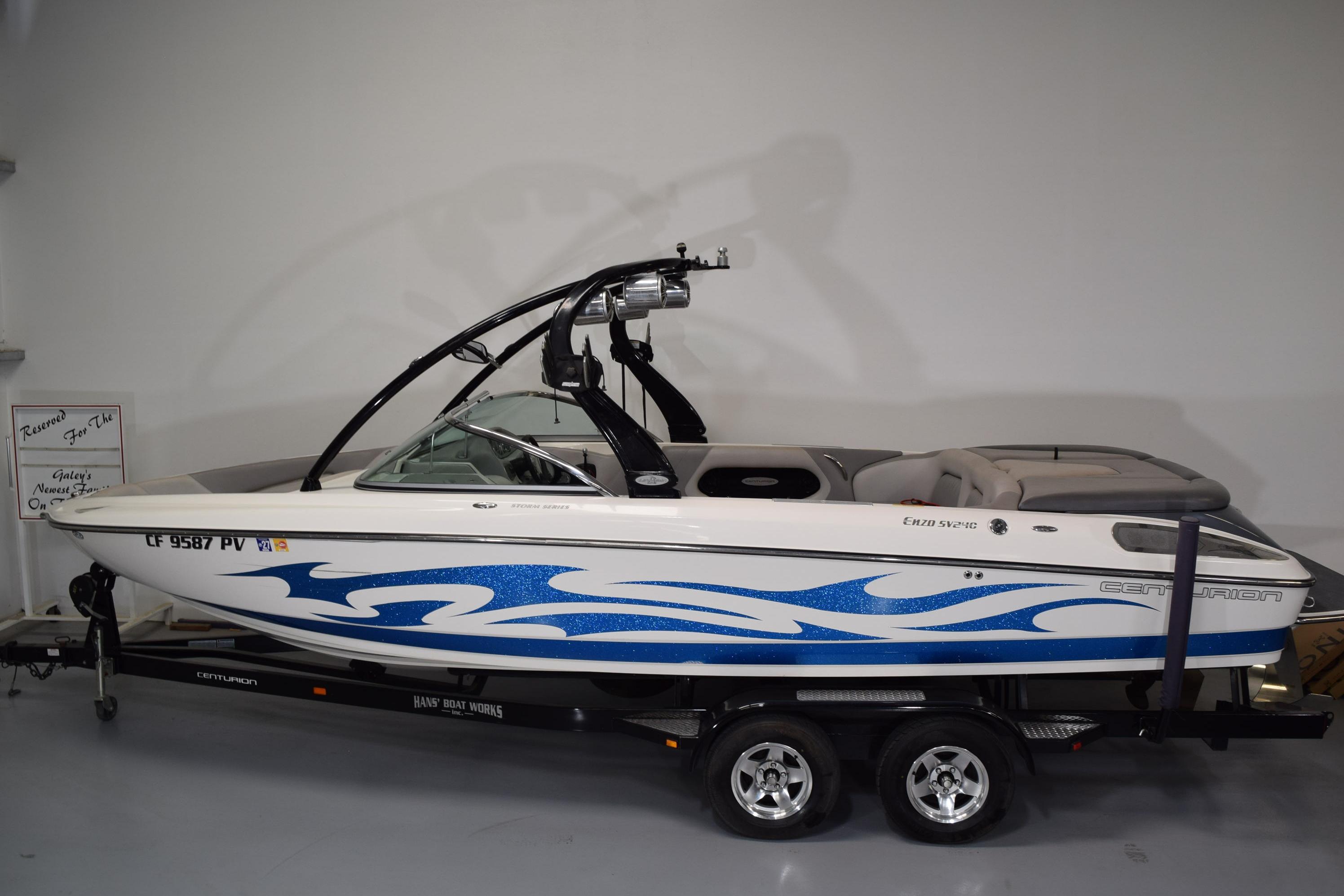 2007 Centurion SV 240 boat with blue wave design on trailer in showroom.