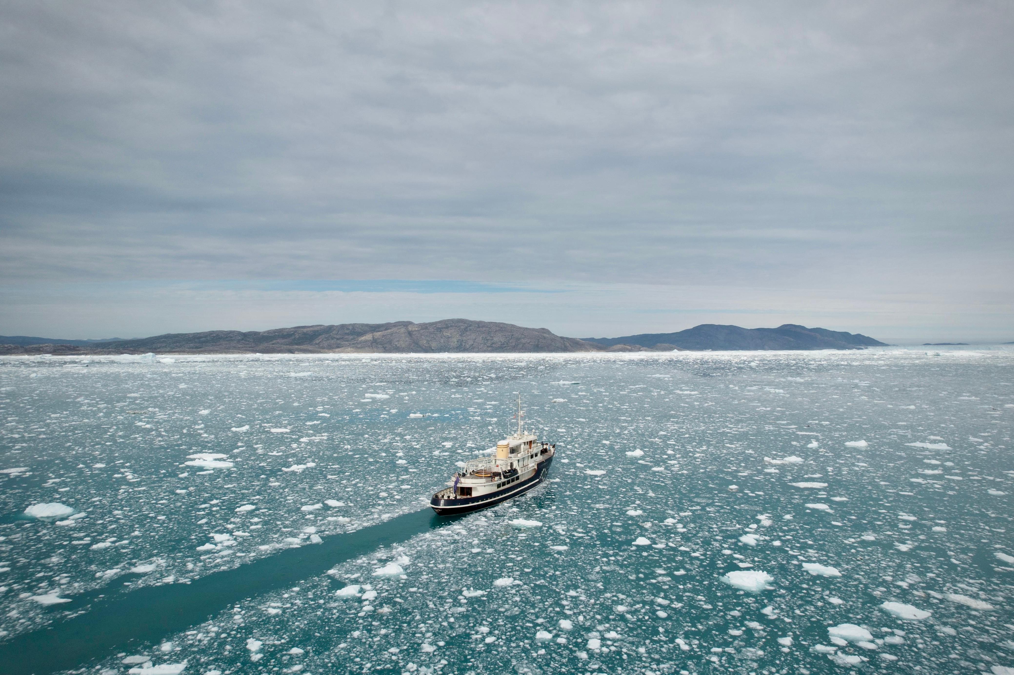 A 1956 custom converted tug navigates icy waters under a cloudy sky.