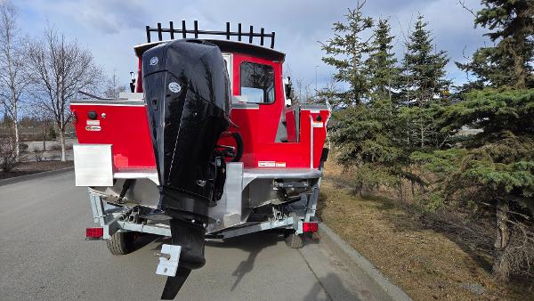 2024 Spartan 220 Maximus boat with outboard motor on a trailer, parked near trees.