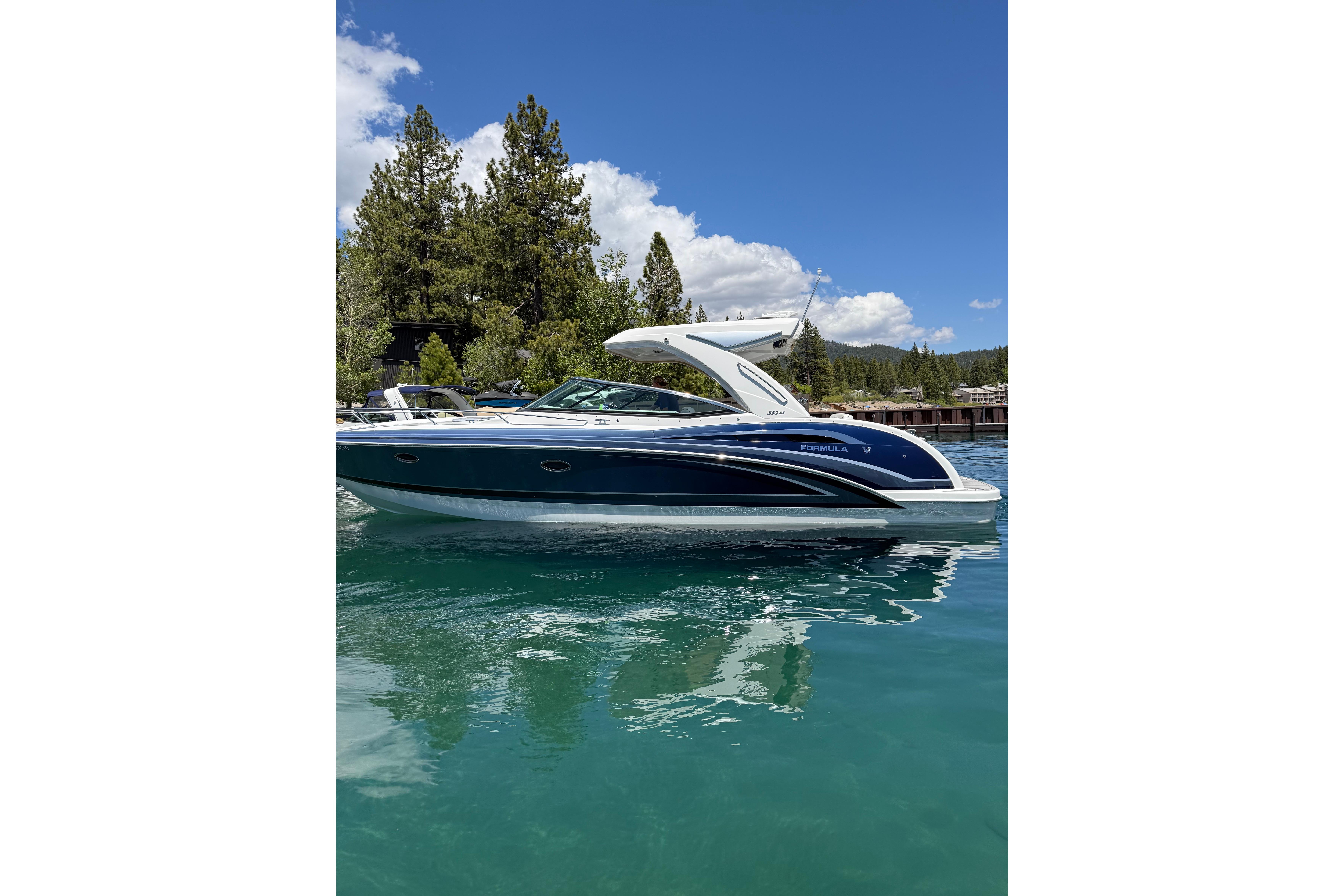 2021 Formula 350 Sun Sport boat on clear water, surrounded by trees and blue sky.