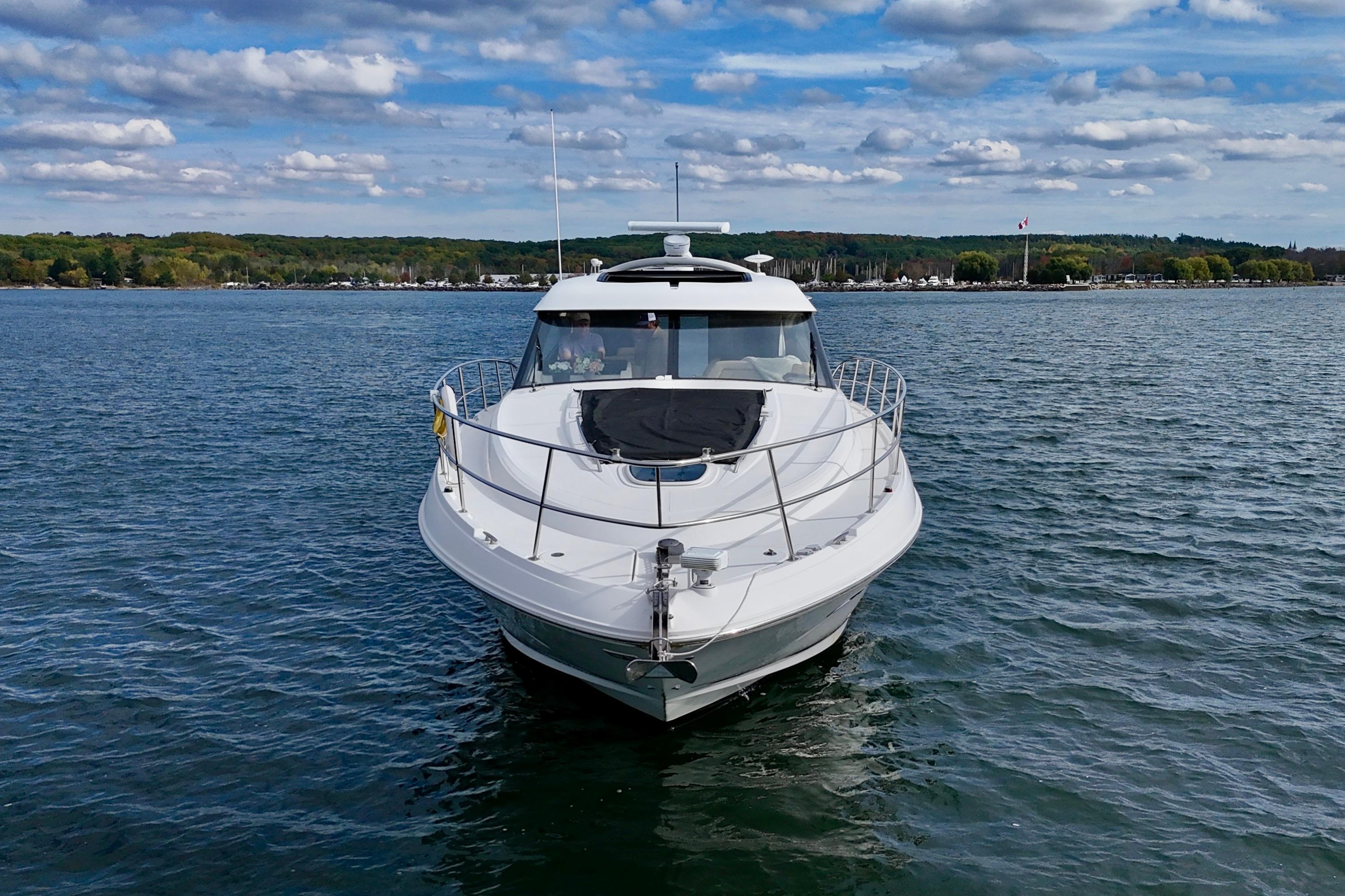 2015 Sea Ray 470 Sundancer yacht on a calm lake under a partly cloudy sky.
