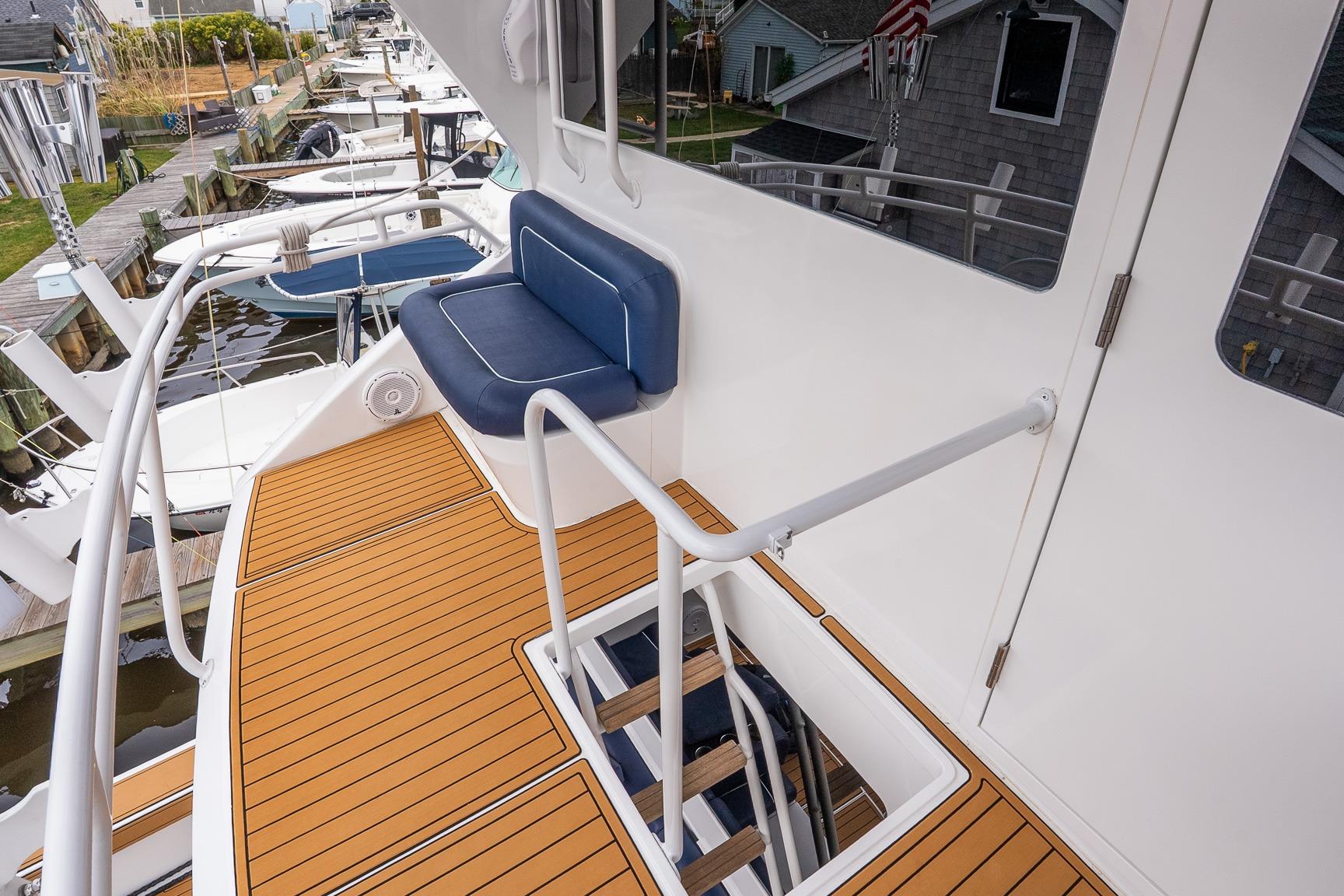2002 Viking 61 Enclosed Bridge yacht with teak deck and blue cushioned seating.