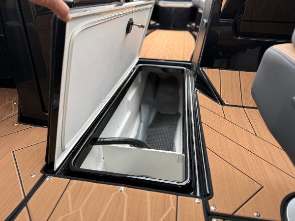 2025 Yamaha Boats 255XD storage compartment with open hatch on wooden deck.