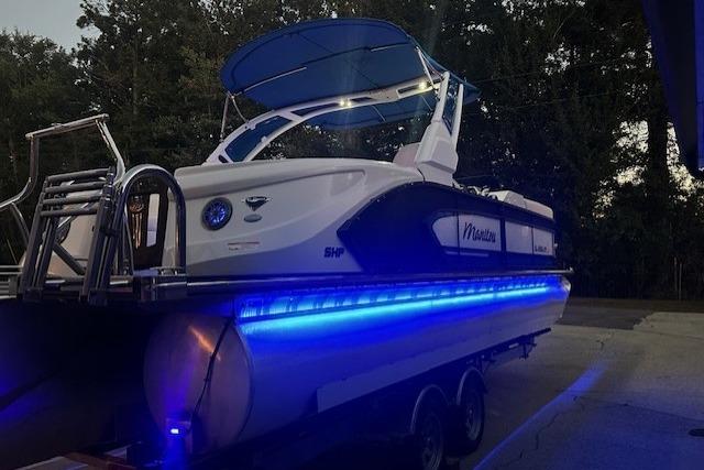 2020 Manitou 25 X-Plode RFW pontoon boat with blue LED lights and canopy.
