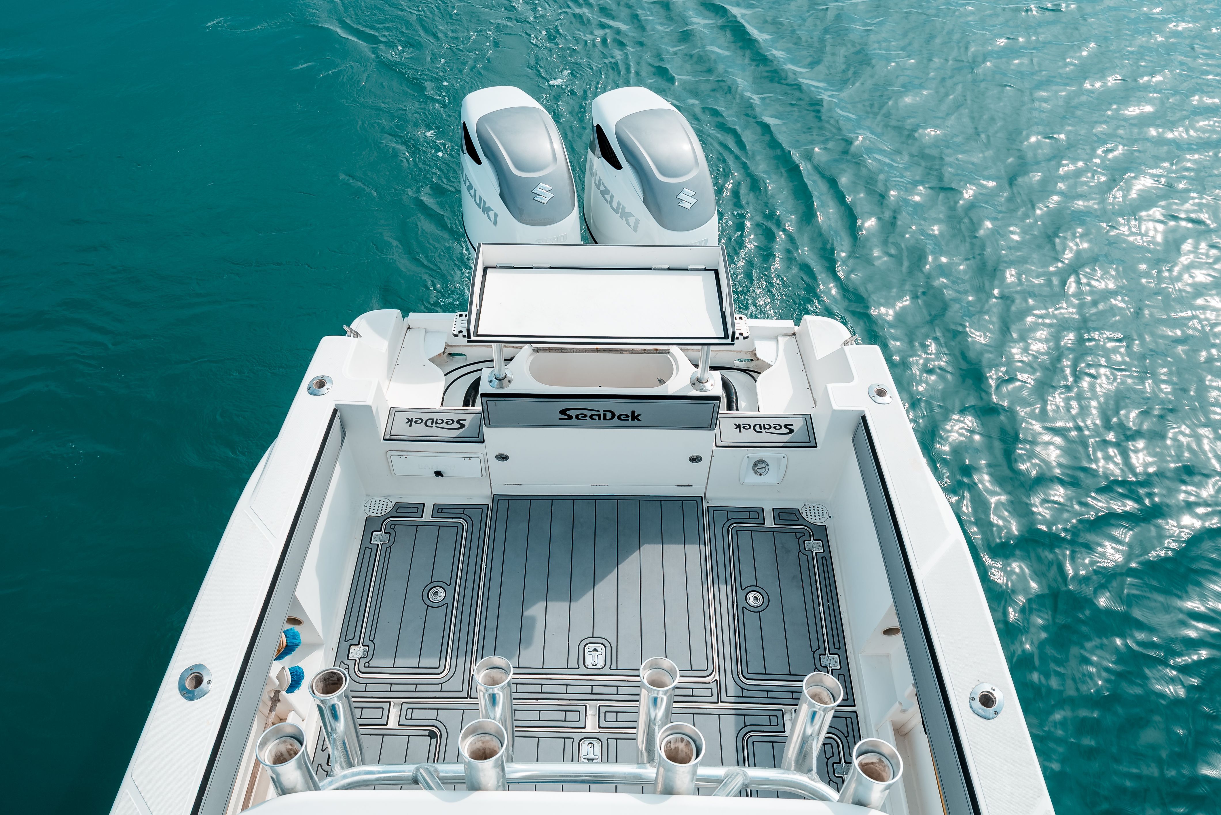 The image shows the stern of a boat with two outboard motors on calm water.