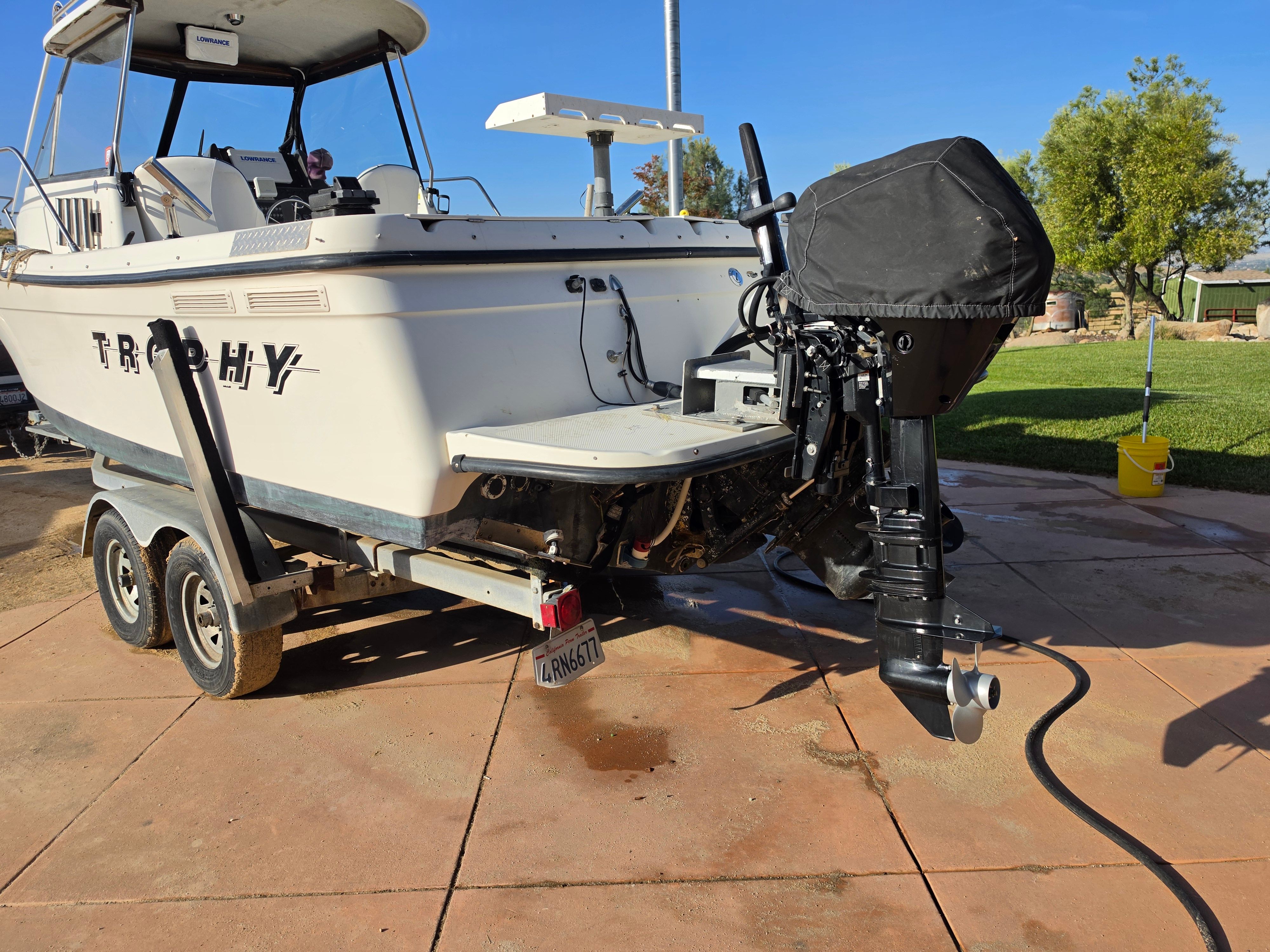 A 2001 Bayliner 2352 Trophy Walkaround on a trailer, with a covered outboard motor.