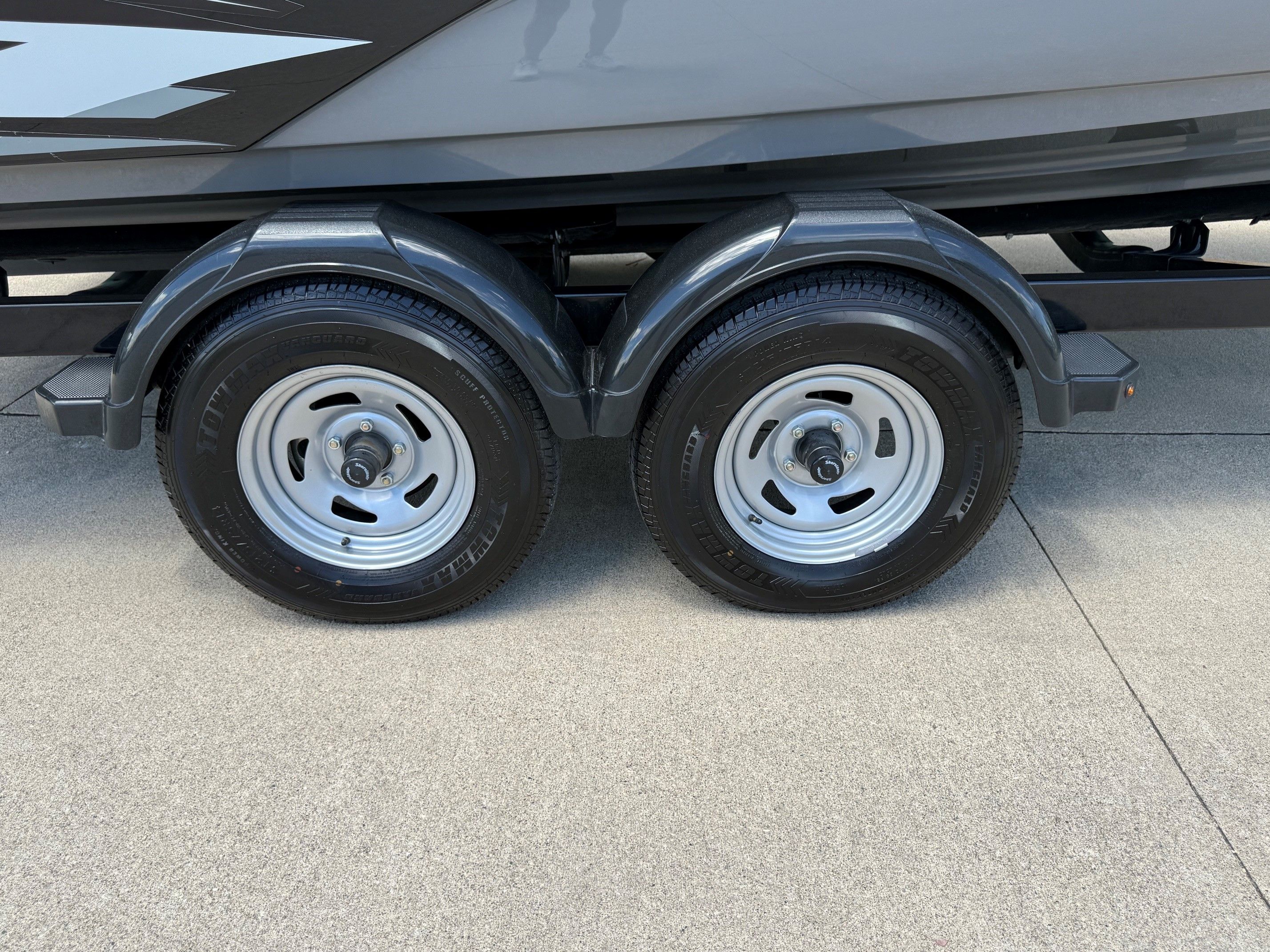 A Yamaha SX210 boat on a trailer with two wheels on concrete ground.