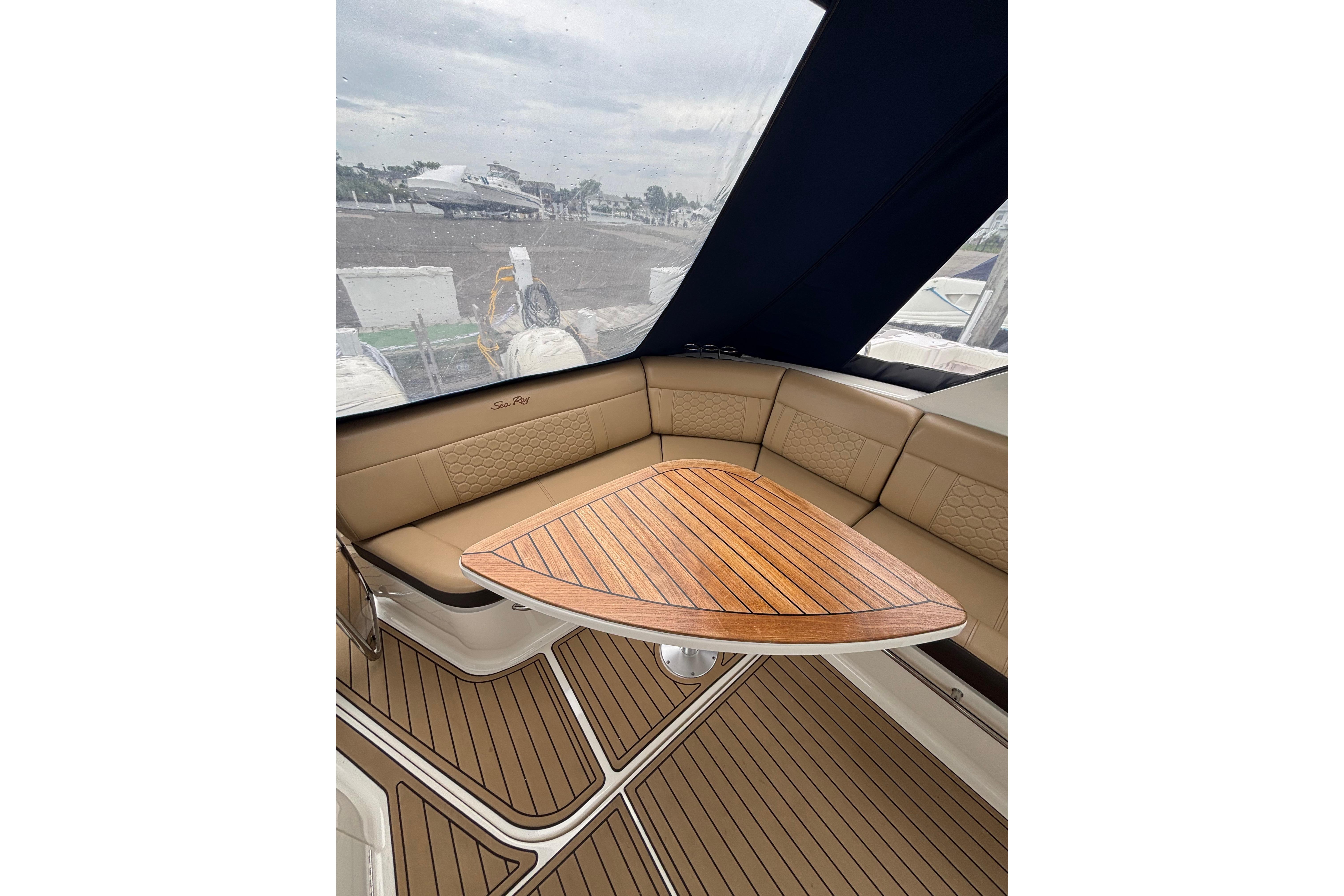 Interior of 2021 Sea Ray Sundancer 320 Outboard with elegant wood table and cushioned seating.