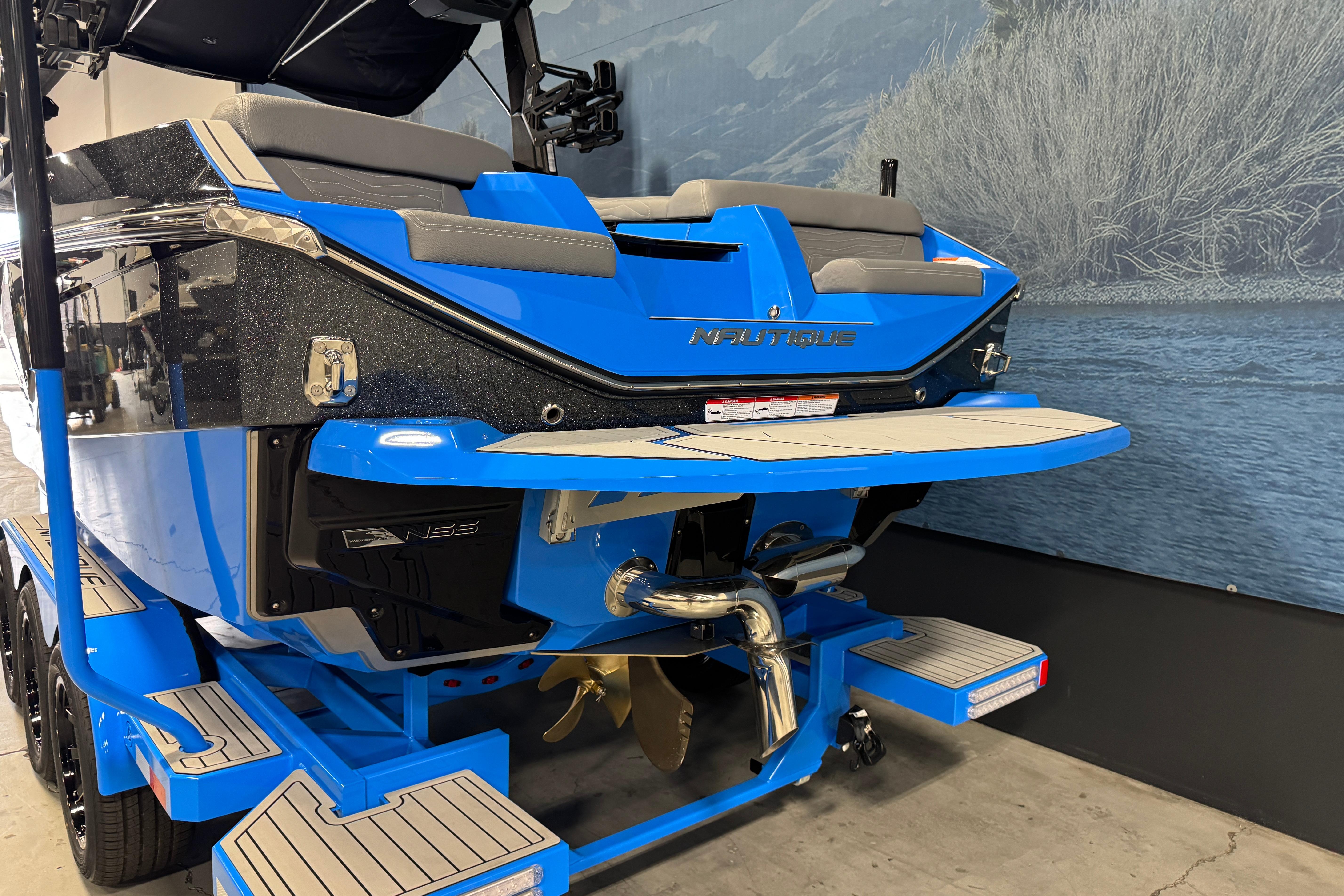 2026 Nautique Super Air Nautique G25 boat, blue exterior, rear view in showroom.