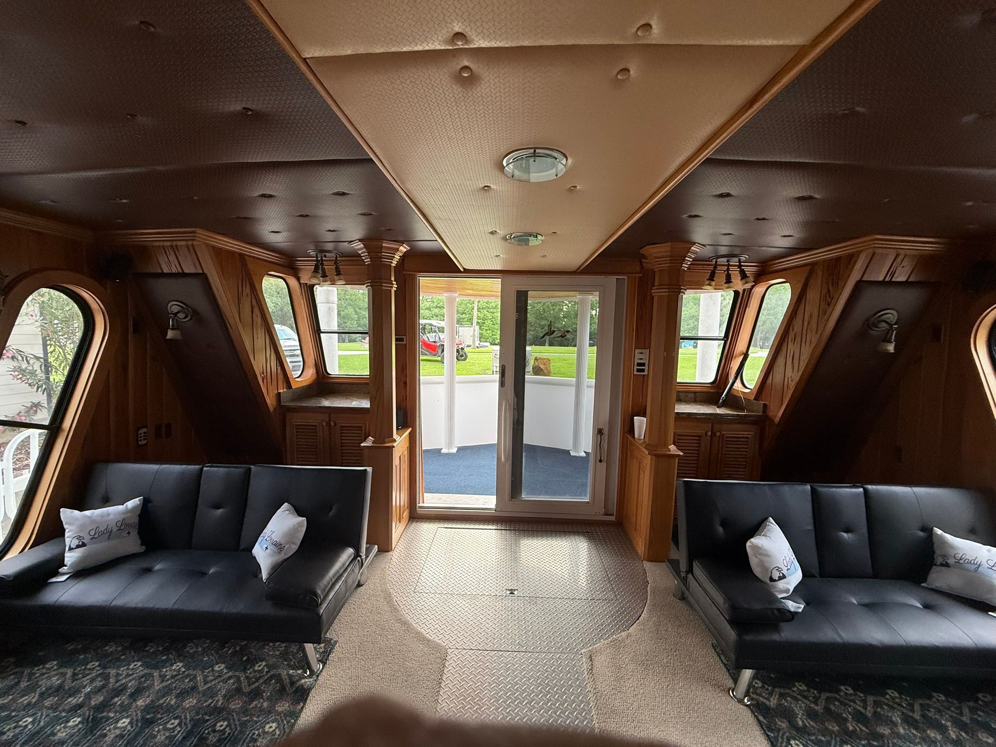 Interior of a boat with two black sofas and wooden walls.