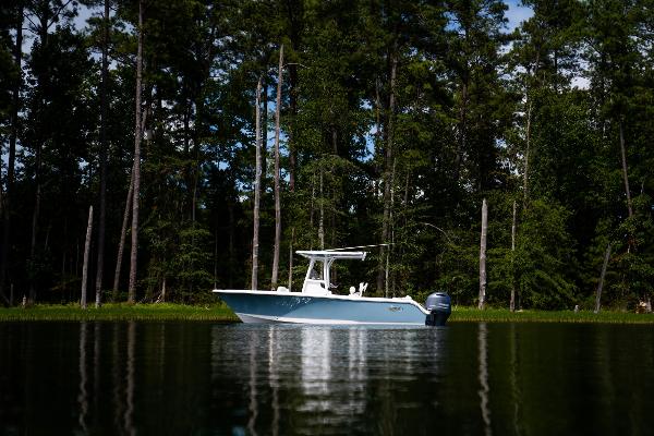2024 Sea Hunt Ultra 234 boat on a calm lake with forest background.