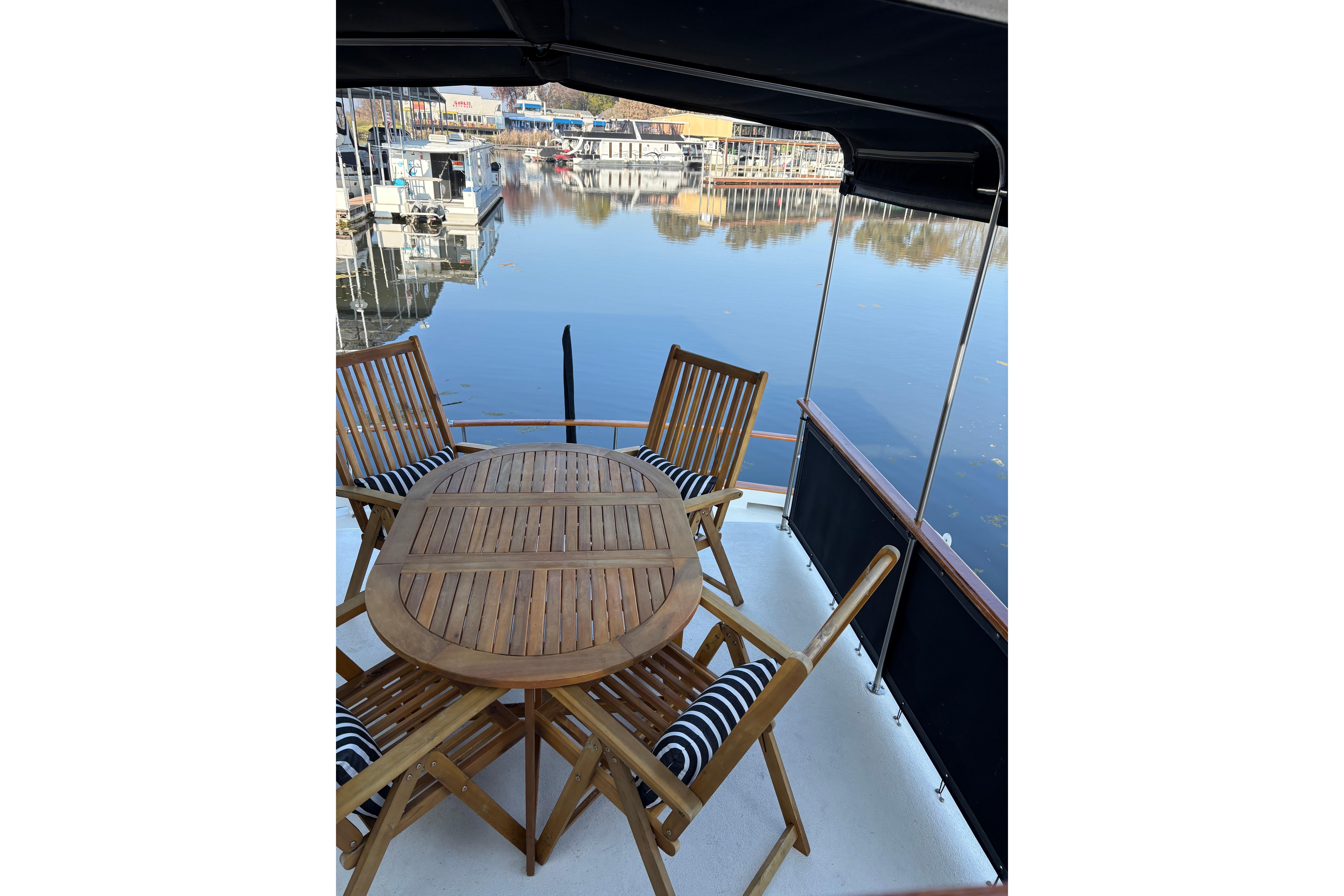 1978 Californian 42 LRC yacht deck with wooden table and chairs overlooking marina.