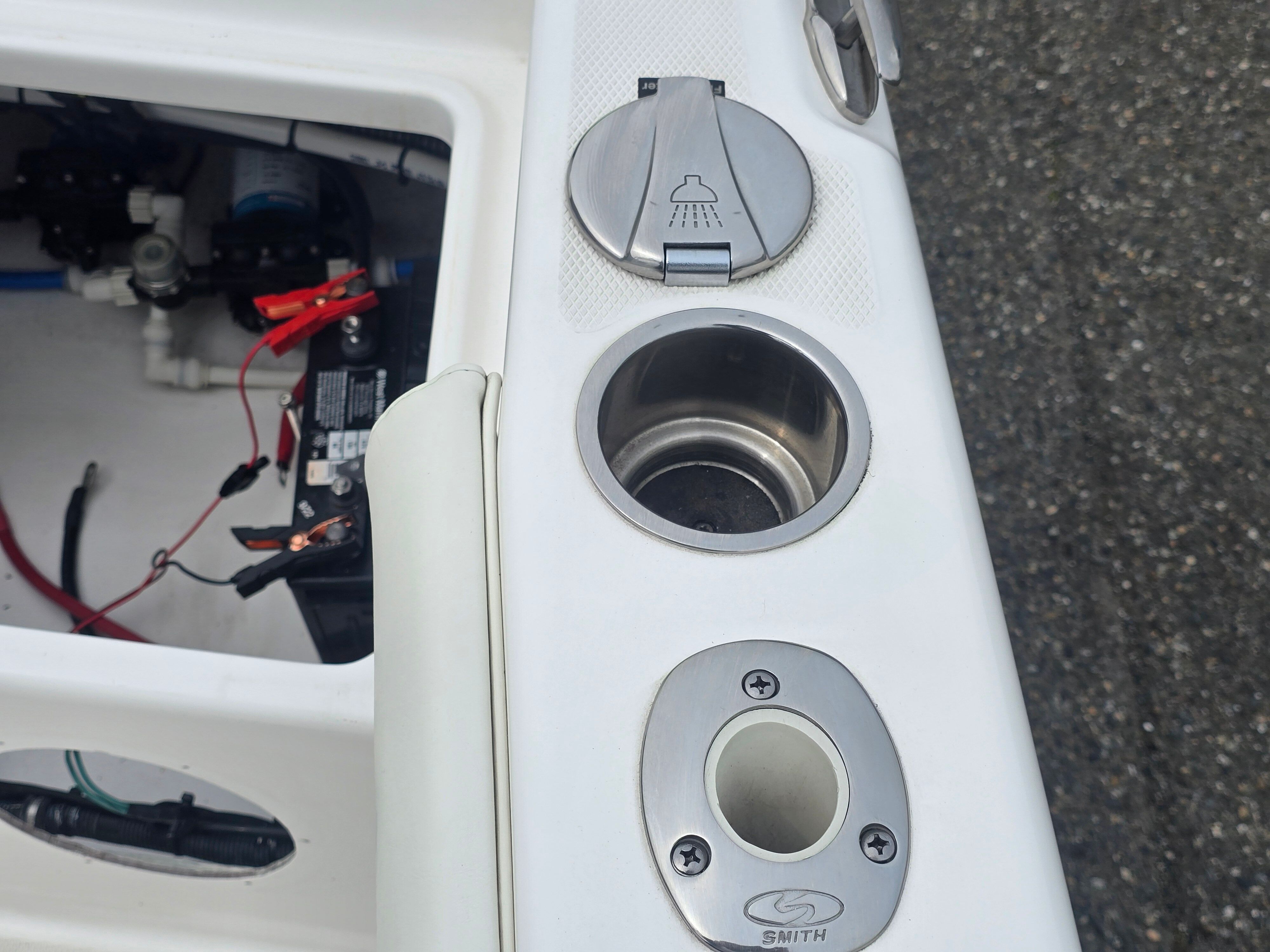 Close-up of a boat deck with a shower head and cup holder.
