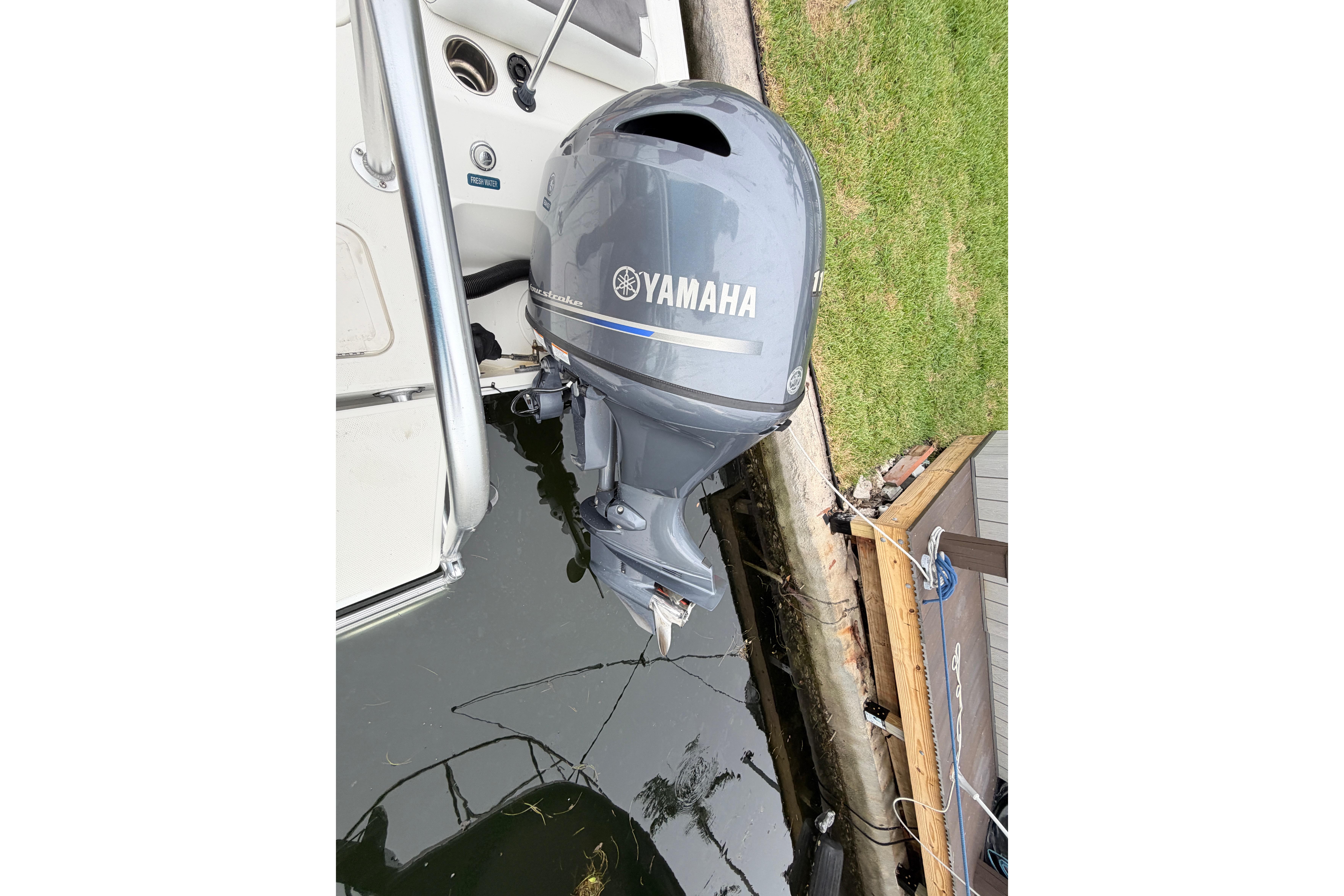 2019 World Cat 230 DC with Yamaha outboard motor docked by grassy shore.
