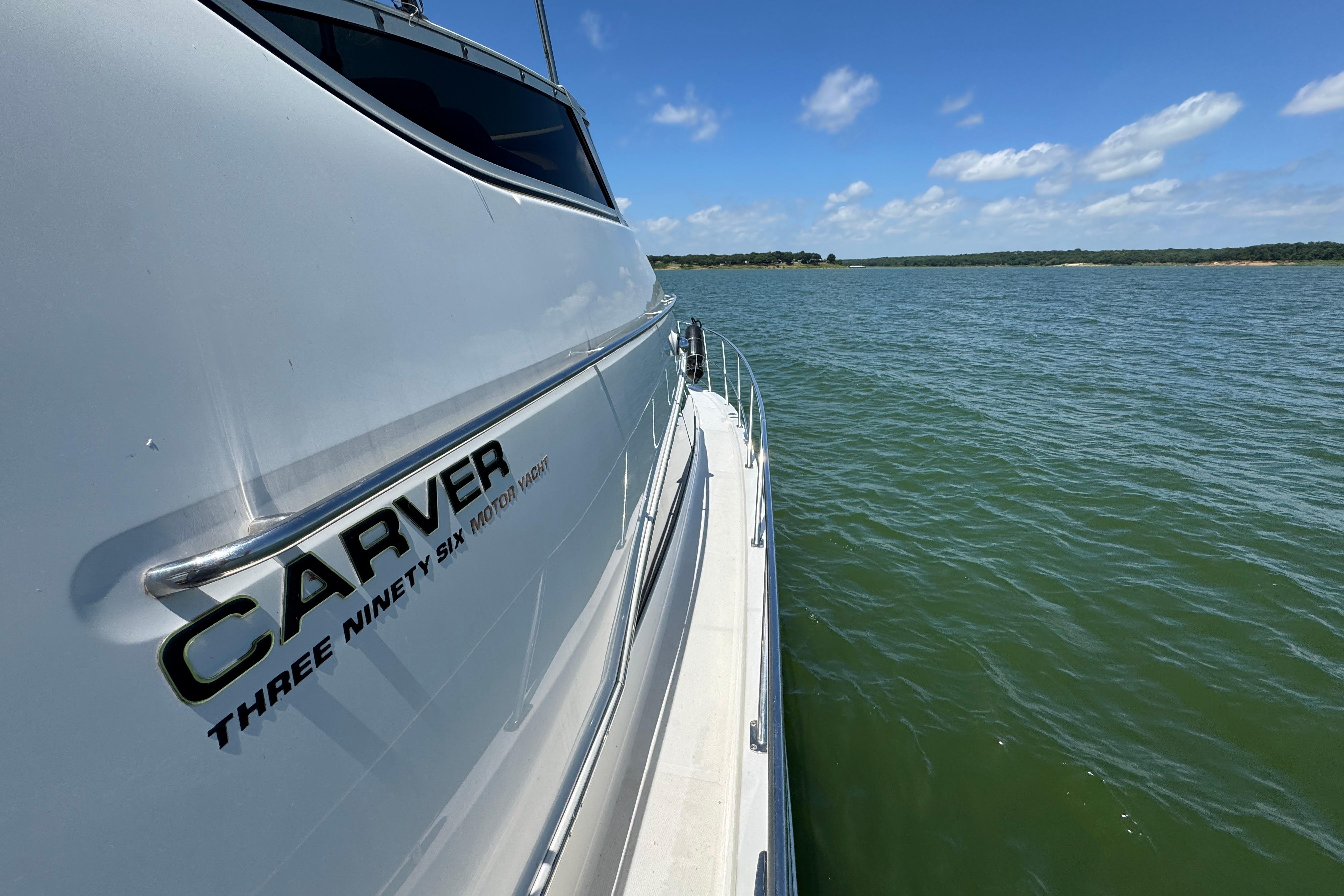 2002 Carver 396 Motor Yacht cruising on a serene lake under a clear blue sky.