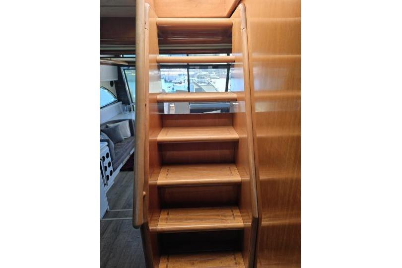 Wooden staircase inside a 1997 Ferretti Yachts 70, leading to upper deck.