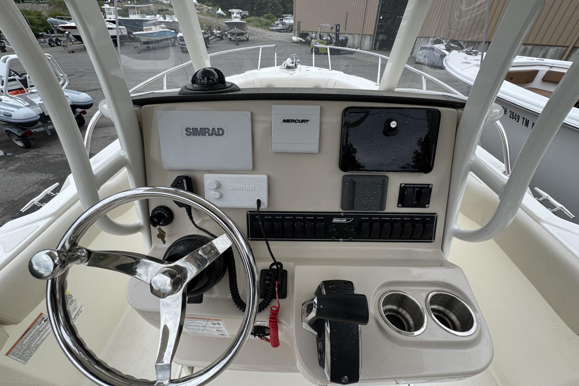 2024 Boston Whaler 230 Outrage helm with steering wheel, Simrad electronics, and Mercury controls.