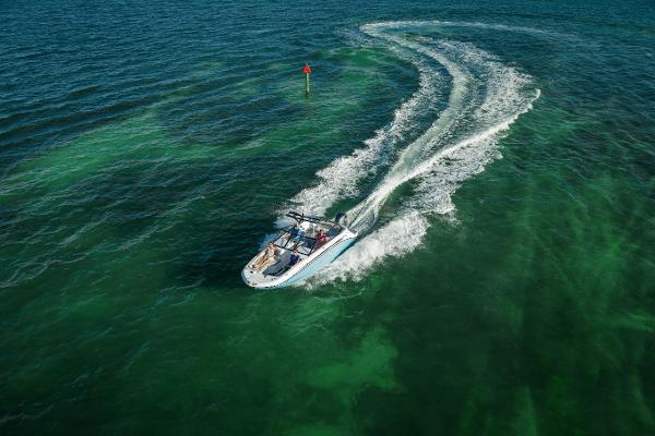 2025 Hurricane SunDeck 235 OB cruising on clear green waters.