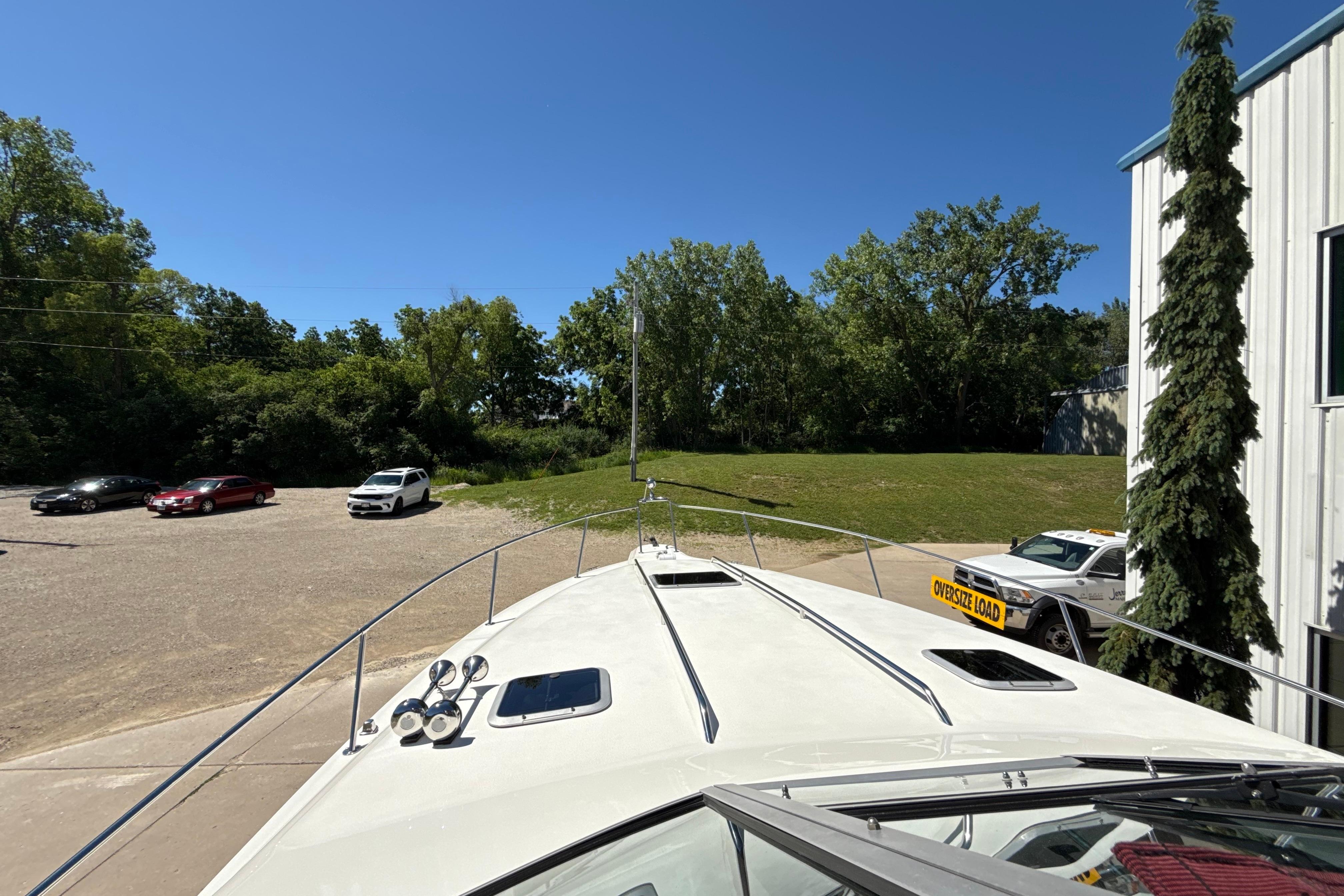 1990 Sea Ray 310 Express Cruiser docked near a parking lot with trees in the background.