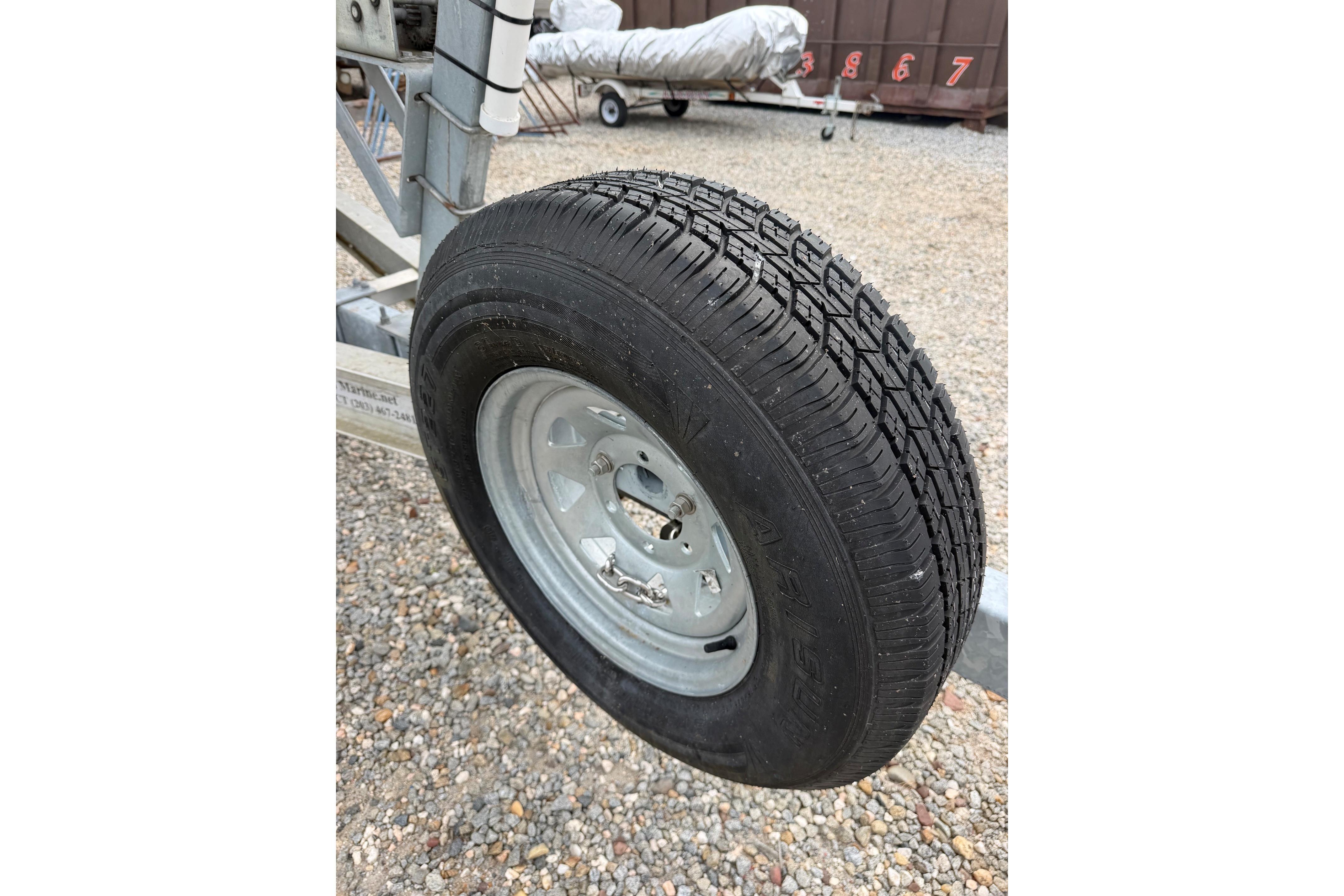 Trailer wheel for 2000 Sea Ray 240 Sundancer on gravel surface.
